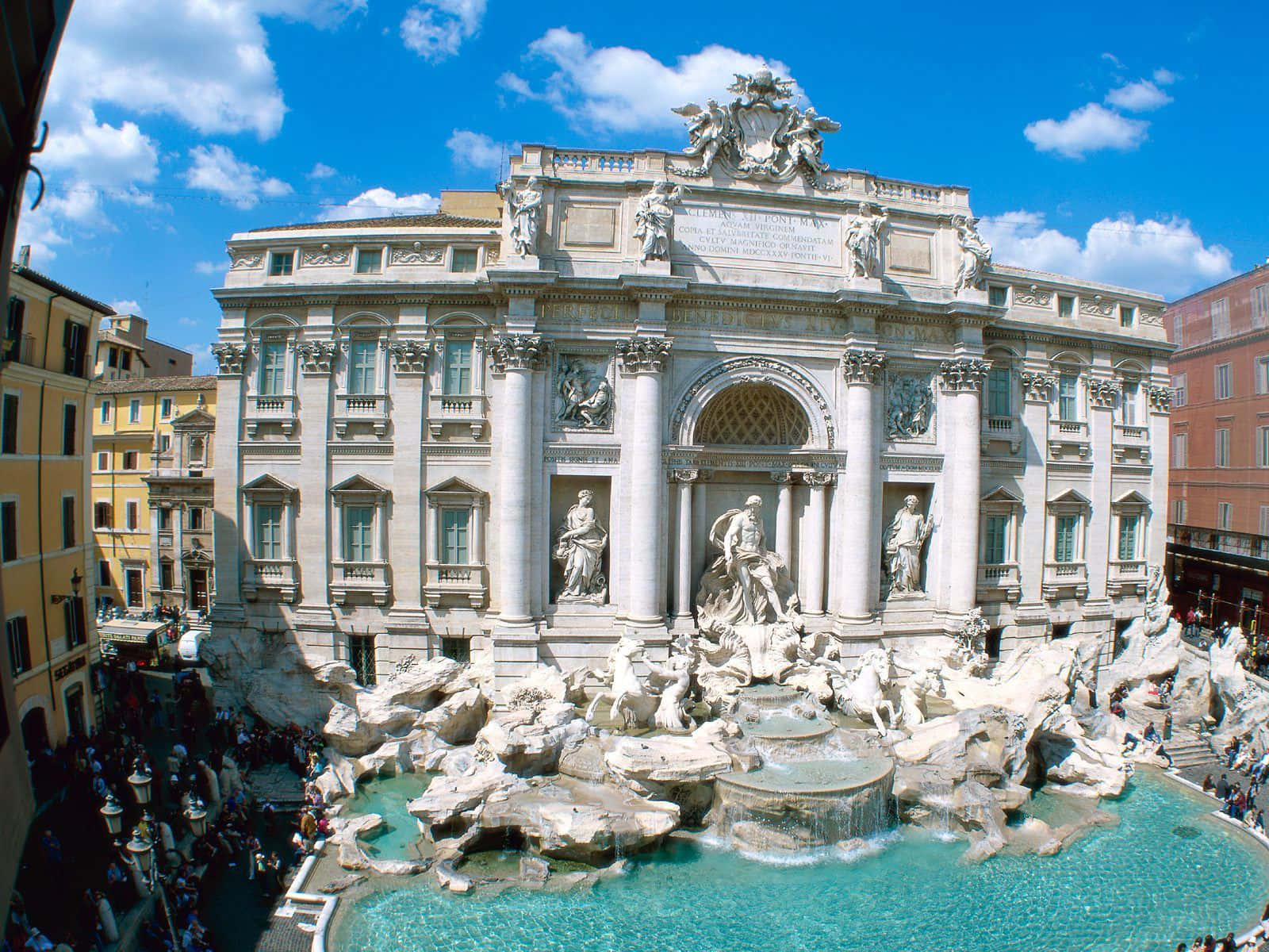 Rome 桌布 壁紙 — 羅馬的特雷維噴泉在明亮的藍天白雲下閃耀，遊客聚集在其華麗的大理石雕像和層疊的藍綠色水周圍。