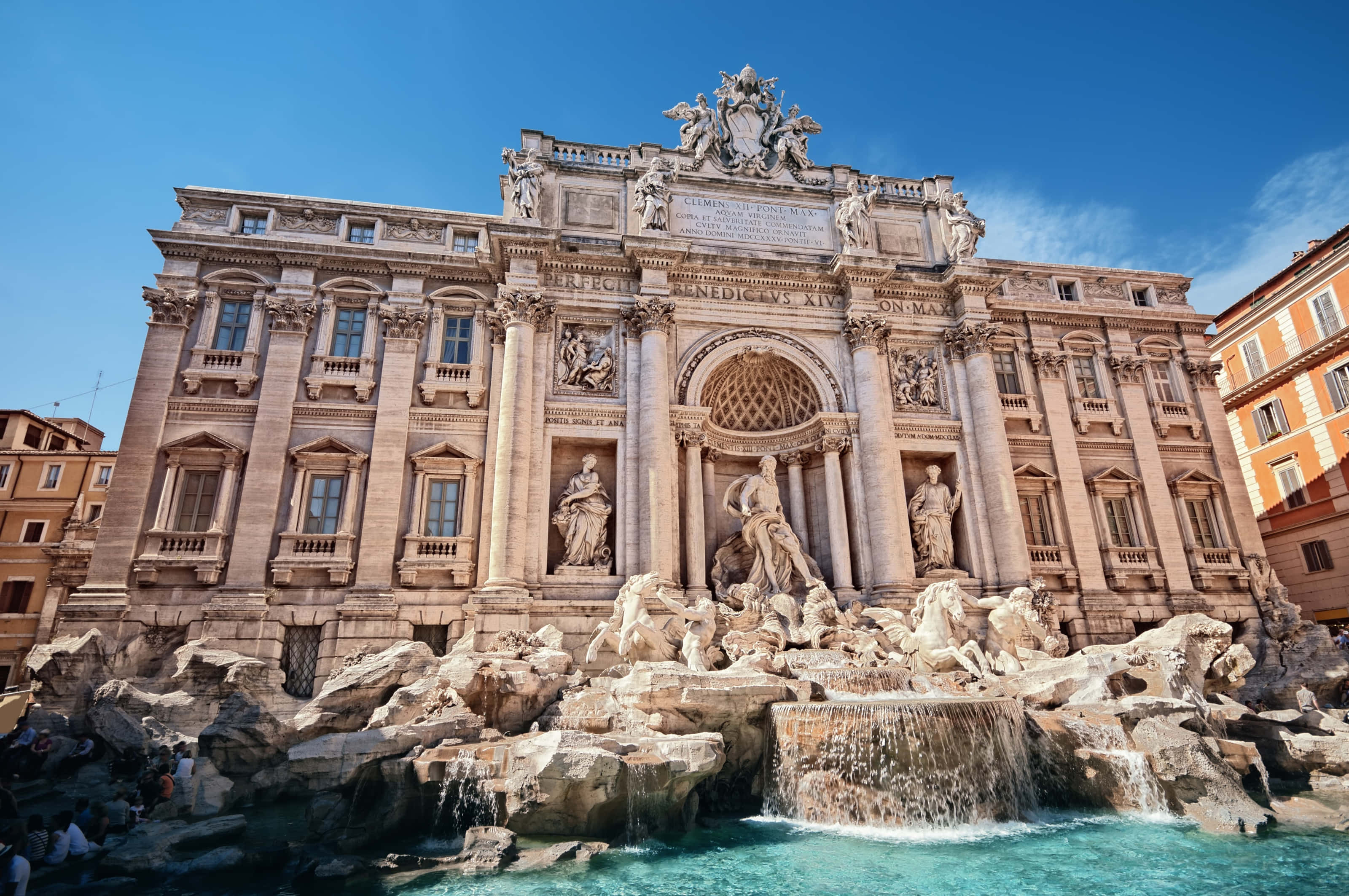 Rome 桌布 壁紙 — 羅馬的特雷維噴泉沐浴在明亮的陽光下，水流傾瀉而下，華麗的巴洛克雕塑在清澈的藍天下閃耀。