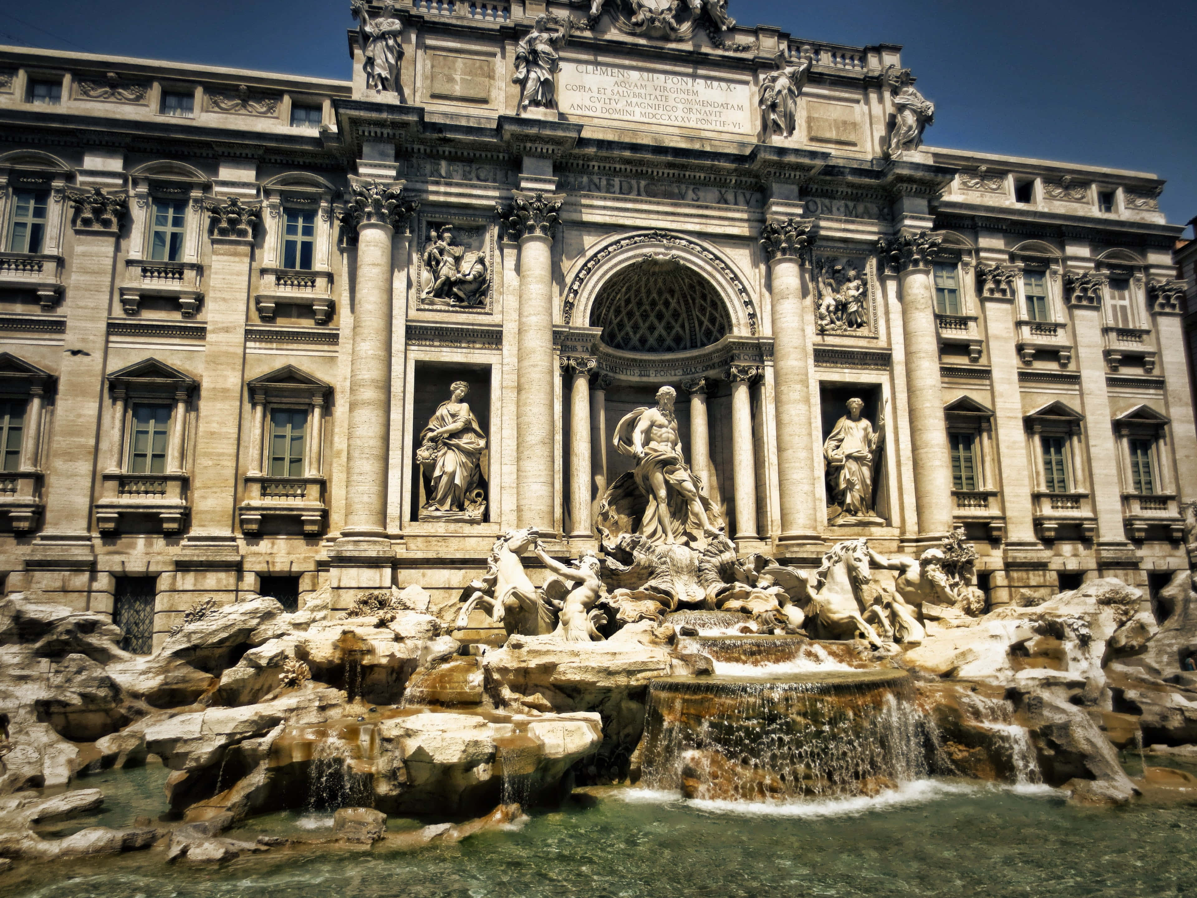 Rome 桌布 壁紙 — 羅馬的特雷維噴泉沐浴在明亮的陽光下，水流傾瀉而下，華麗的巴洛克雕塑點綴其間。