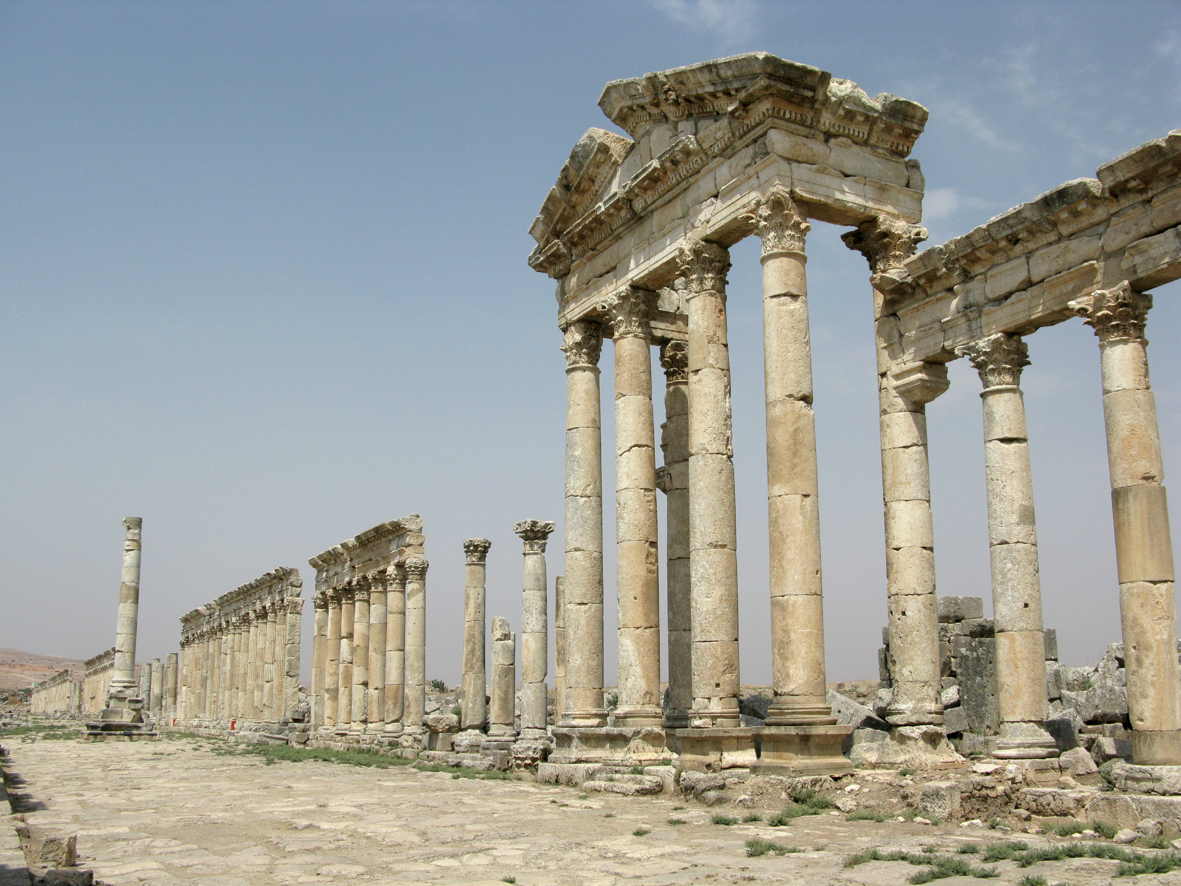 Syria 桌布 壁紙 — 羅馬神廟的古老石柱在陽光明媚的考古遺址中，高聳於清澈的藍天之下。