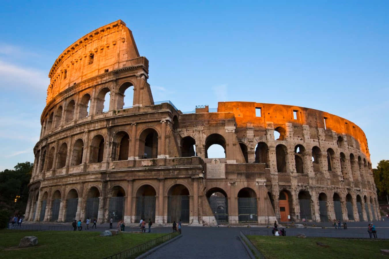 Roman 桌布 壁紙 — 羅馬競技場沐浴在金色夕陽下，遊客探索其古老的石拱門。