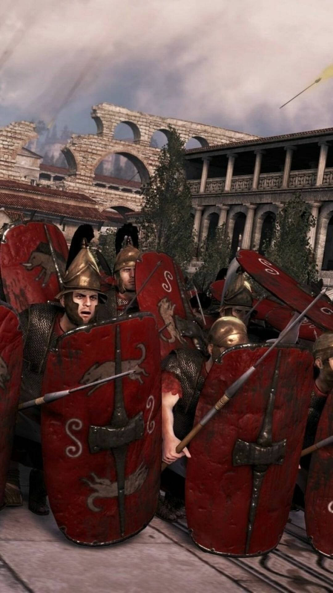 Rome Total War 桌布 壁紙 — 羅馬軍團士兵手持紅色盾牌、戴著青銅頭盔，在塵土飛揚的競技場中交戰，古老的石拱門在頭頂若隱若現。