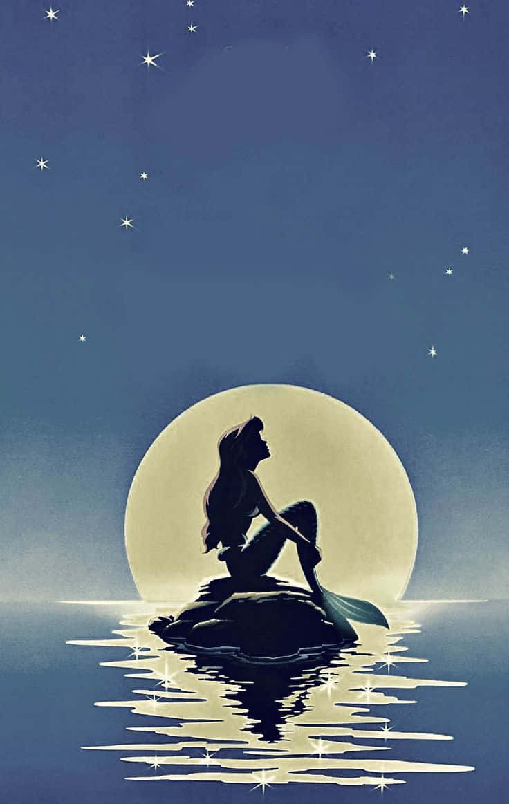 little mermaid 桌布 壁紙 — 美人魚剪影坐在岩石上，下方是發光的月亮和繁星點點的夜空，水面閃爍著倒影。