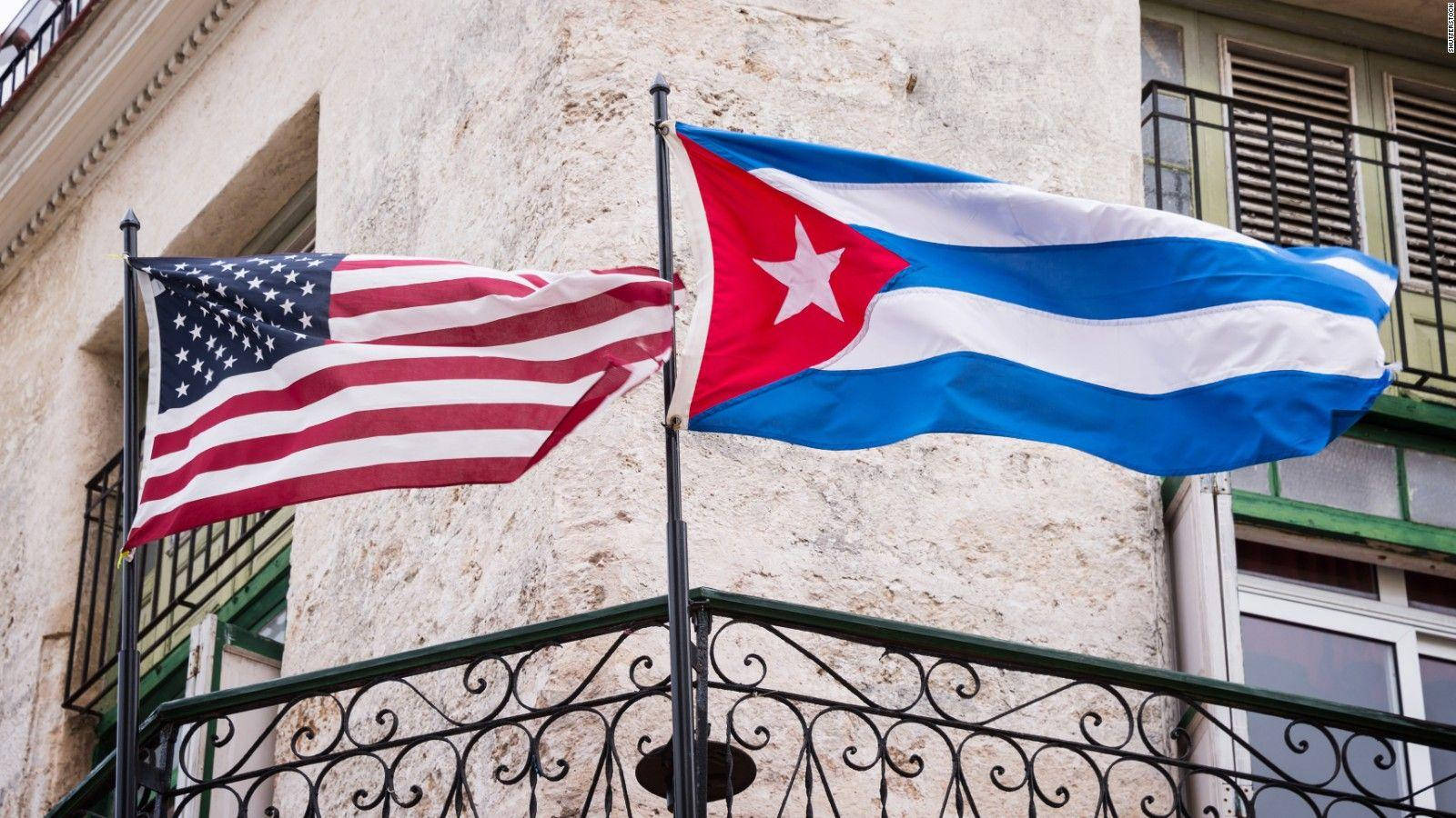 Cuban 桌布 壁紙 — 美國和古巴國旗在風化的建築物外牆和華麗的黑色欄杆旁並排飄揚。