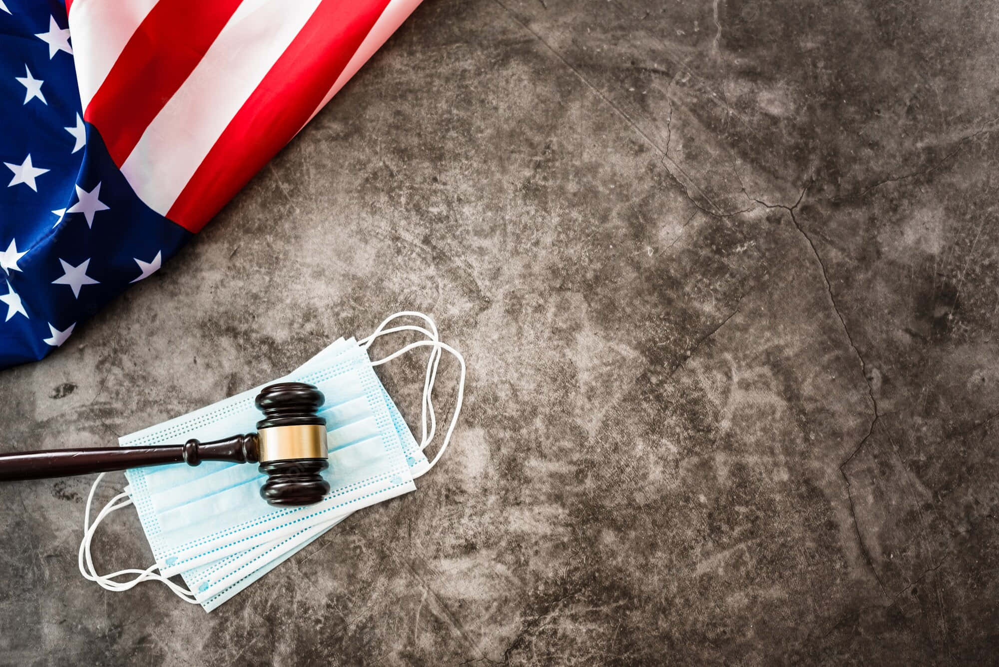 Law Enforcement 桌布 壁紙 — 美國國旗、木槌和外科口罩放在破裂的混凝土表面上。