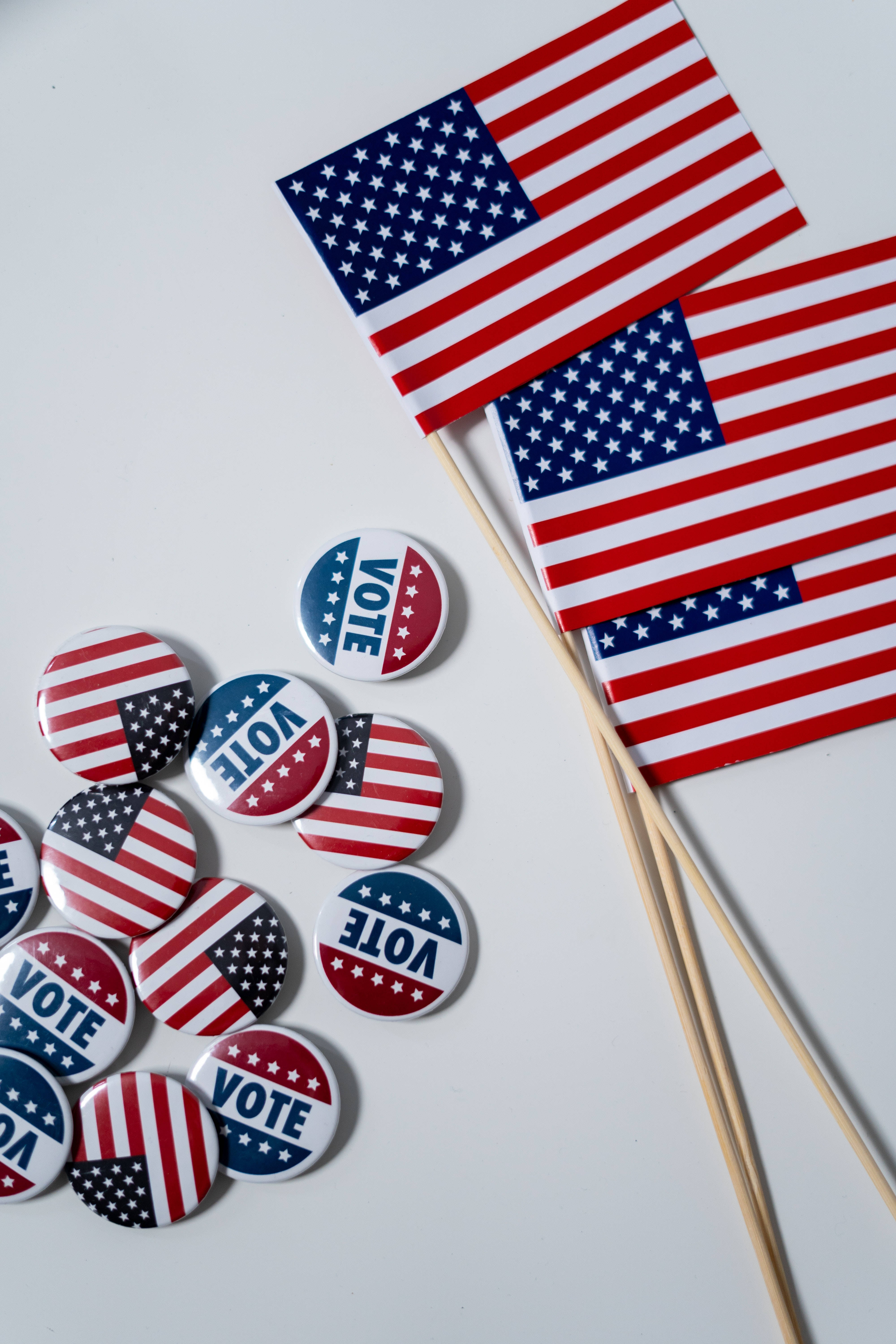 USA 桌布 壁紙 — 美國國旗別針和小旗幟散落在白色表面上，推廣投票。