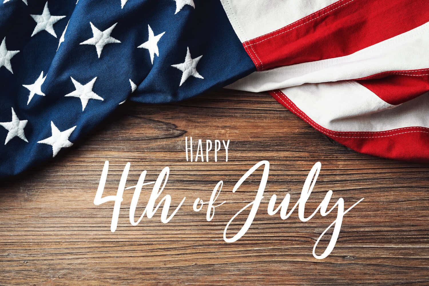 Happy Fourth Of July 桌布 壁紙 — 美國國旗披在質樸的木桌上，白色字體寫著「Happy 4th of July」。