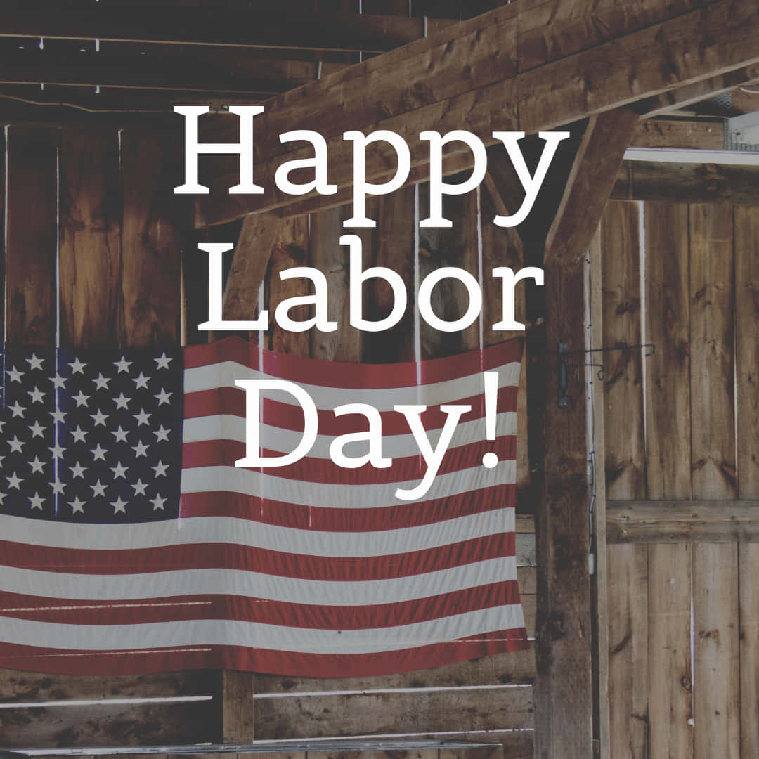 勞動節 桌布 壁紙 — 美國國旗掛在質樸的木穀倉中，帶有「Happy Labor Day!」文字疊加。