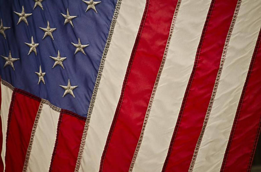 USA flag iPhone 桌布 壁紙 — 美國國旗星條旗的特寫，帶有紋理布料和可見的縫線細節。
