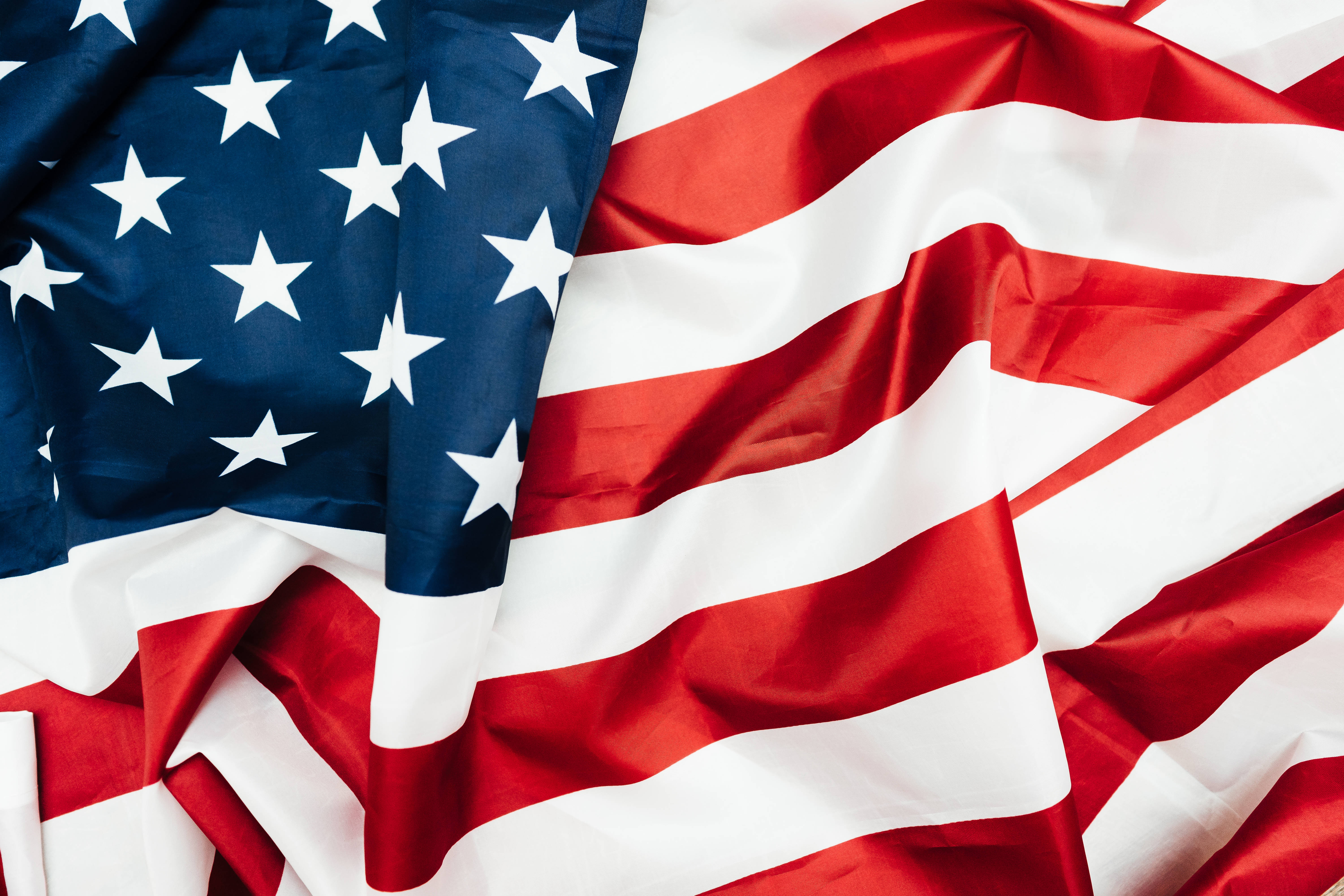 USA flag iPhone 桌布 壁紙 — 美國國旗的特寫，具有質感，紅白藍條紋和星星在柔軟的摺疊中飄揚。
