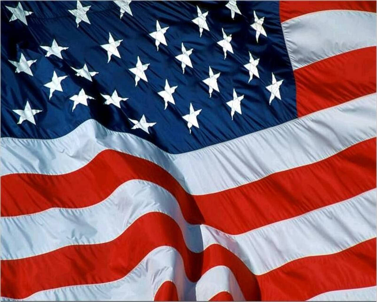 Patriotic 桌布 壁紙 — 美國國旗的特寫，動態飄揚，帶有鮮明的紅、白、藍色和清晰的星星和條紋。