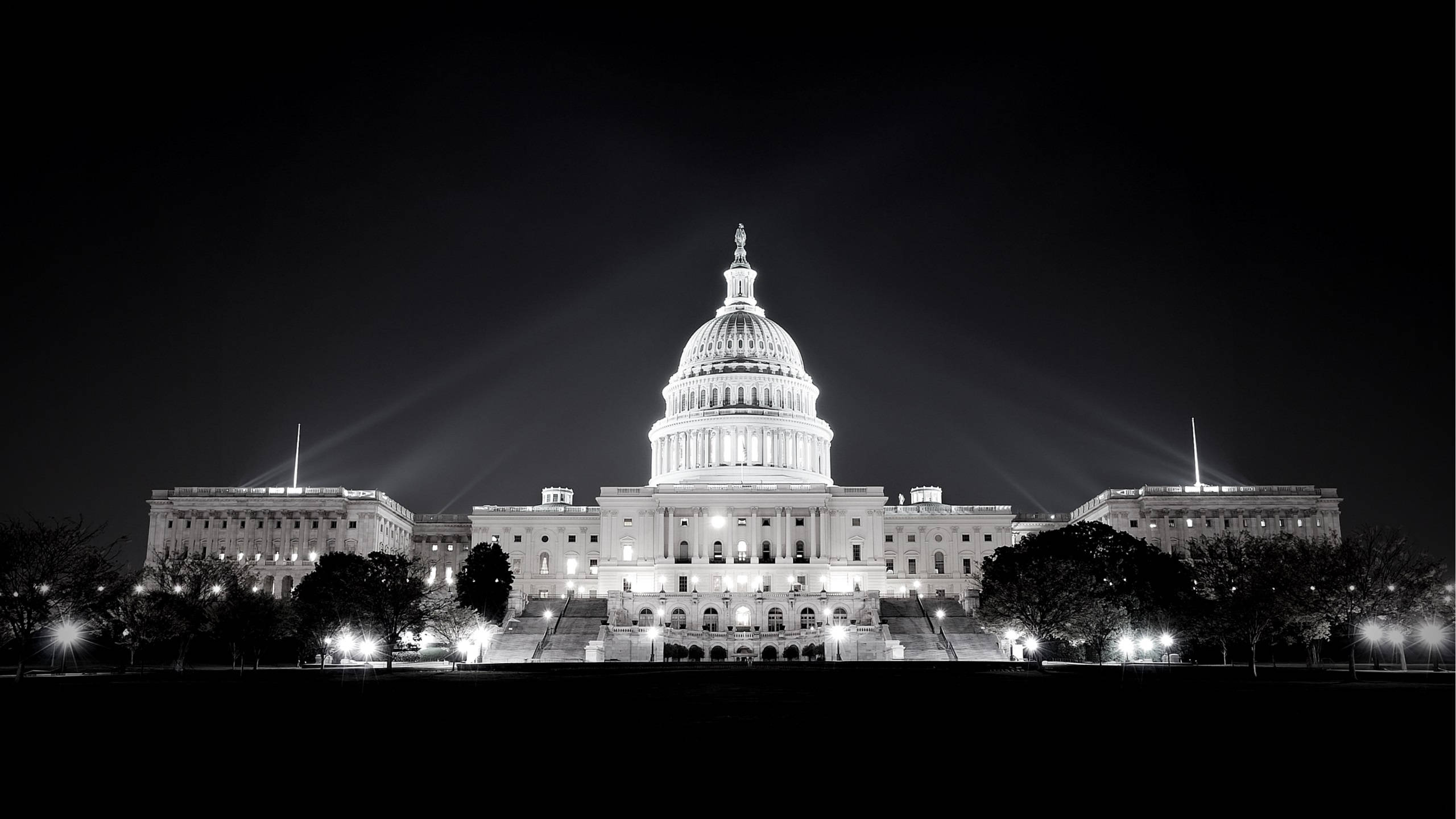 Washington 桌布 壁紙 — 美國國會大廈在夜間被戲劇性的聚光燈照亮，映襯著黑暗的天空。