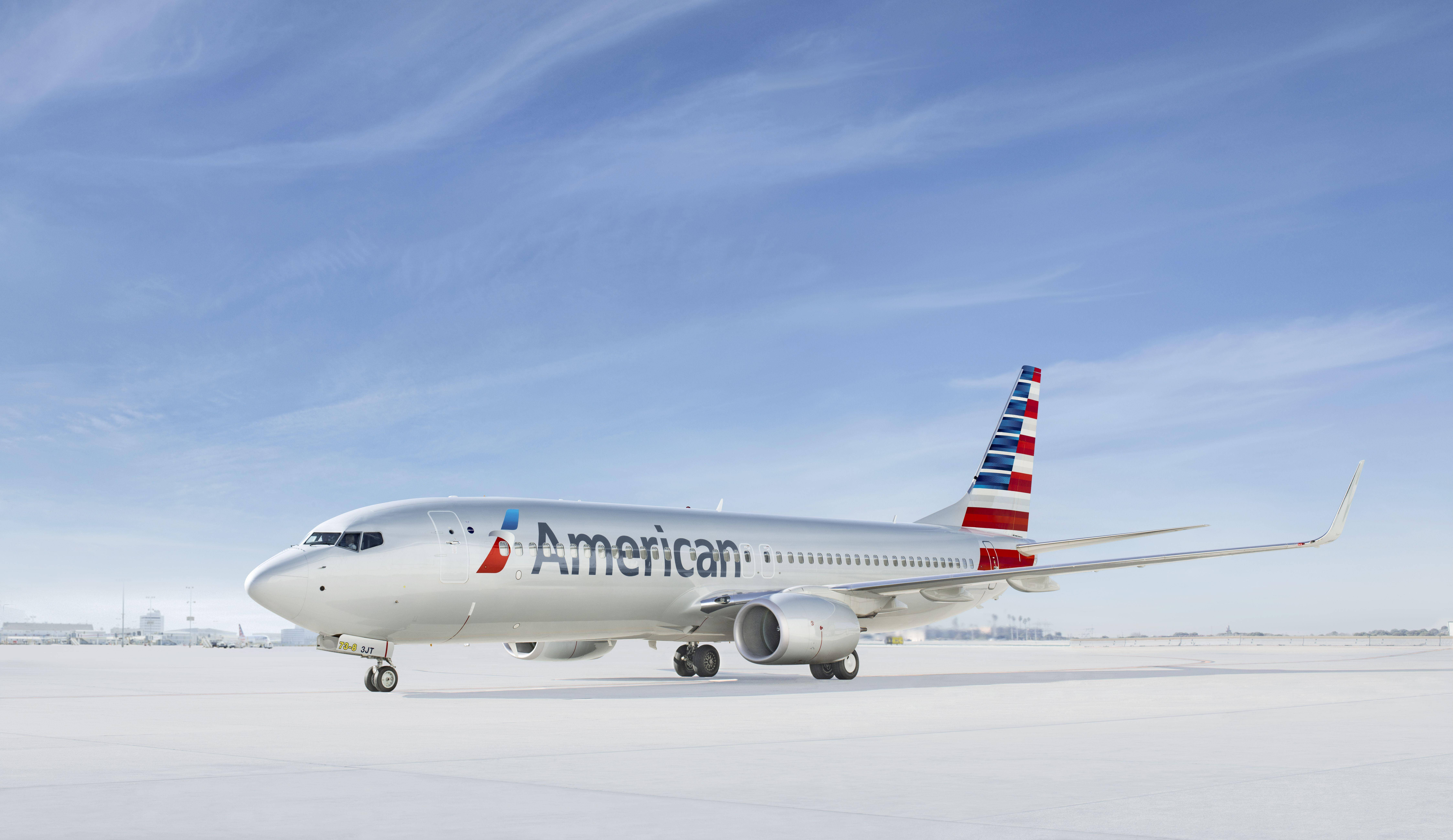Airlines 桌布 壁紙 — 美國航空波音737停放在白雪覆蓋的停機坪上，天空湛藍清澈，飄著幾縷薄雲。