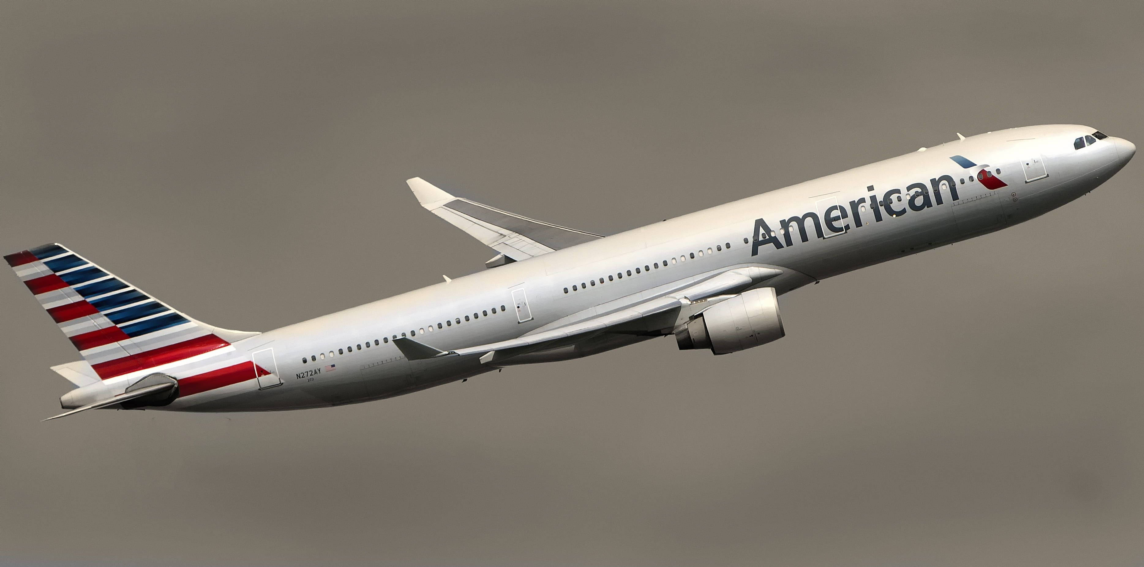 Airlines 桌布 壁紙 — 美國航空的空中巴士A330在暗淡的灰色天空中翱翔，其標誌性的紅白藍尾翼清晰可見。