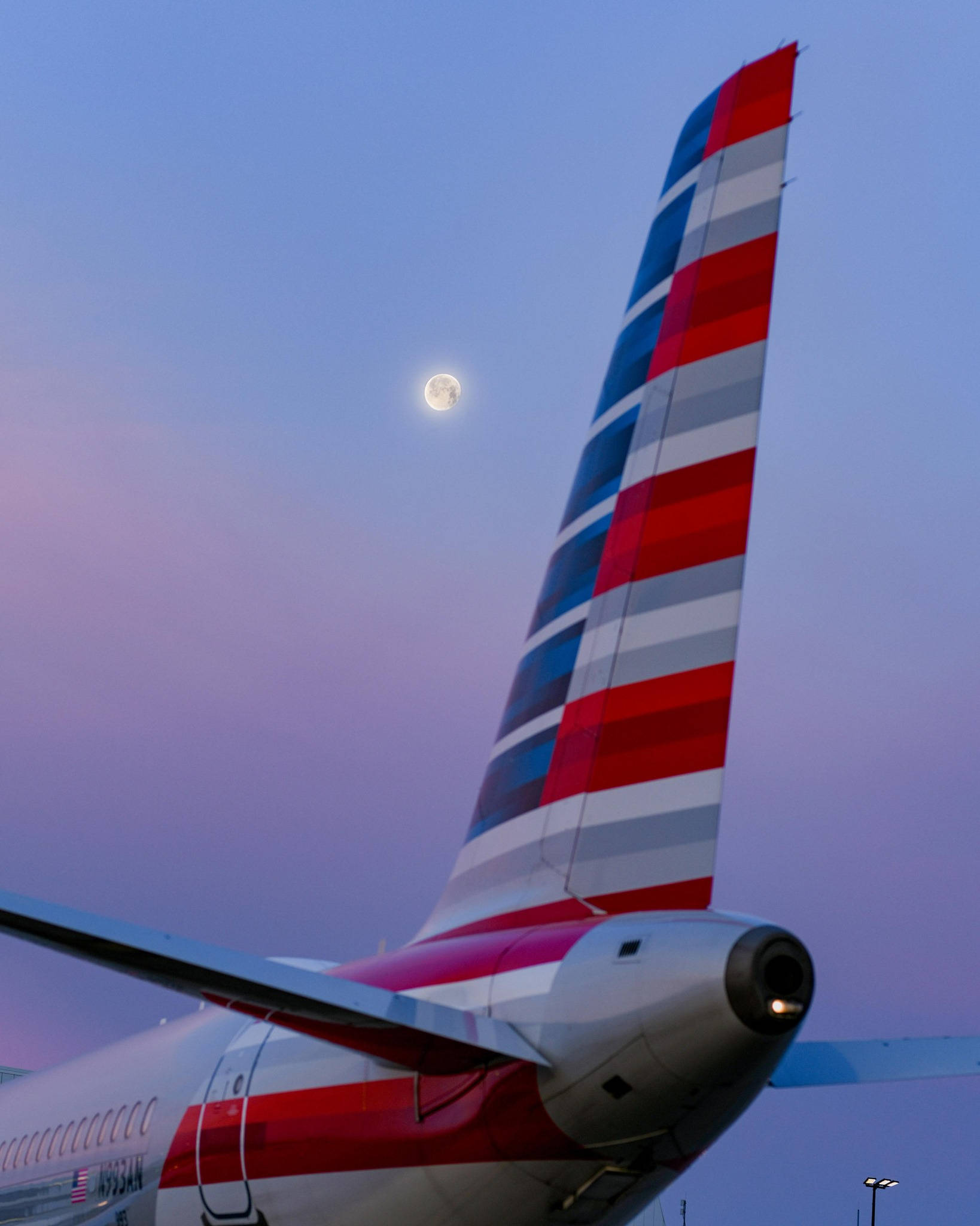 Airlines 桌布 壁紙 — 美國航空飛機尾部，帶有紅白藍條紋，背景為暮色天空和滿月。