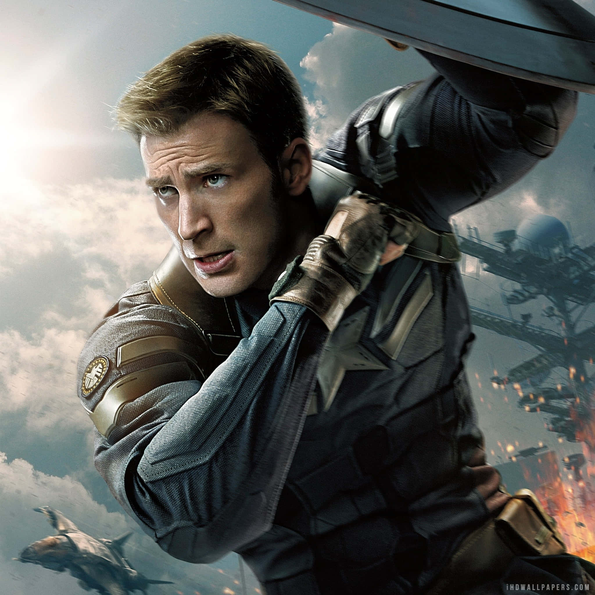 Captain America Movie 桌布 壁紙 — 美國隊長在半空中以熾熱的爆炸和戰火紛飛的天空為背景保護自己。
