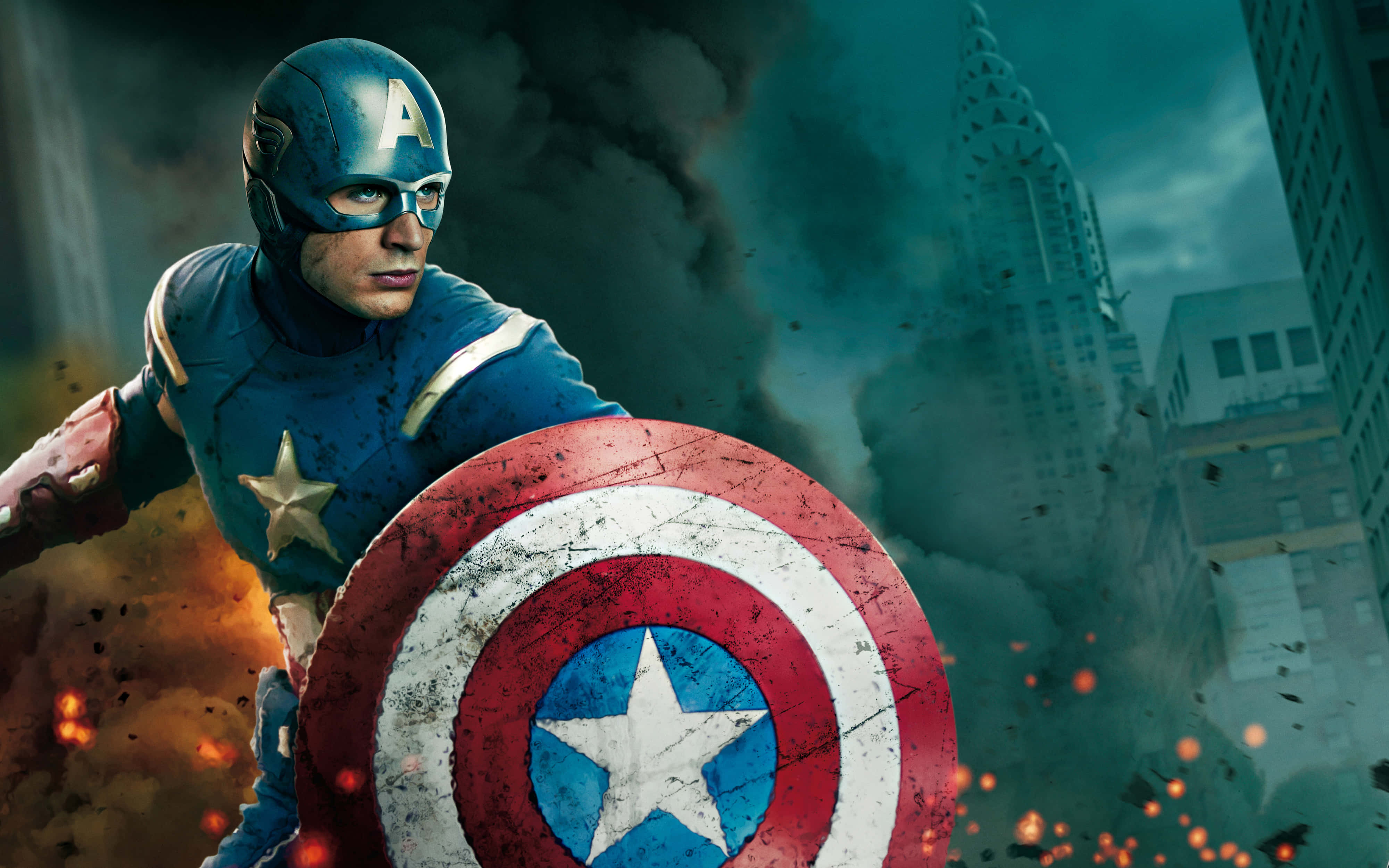 Captain America Desktop 桌布 壁紙 — 美國隊長在戰火摧殘的城市景觀中挑釁地站立，身後煙霧和火焰爆發。