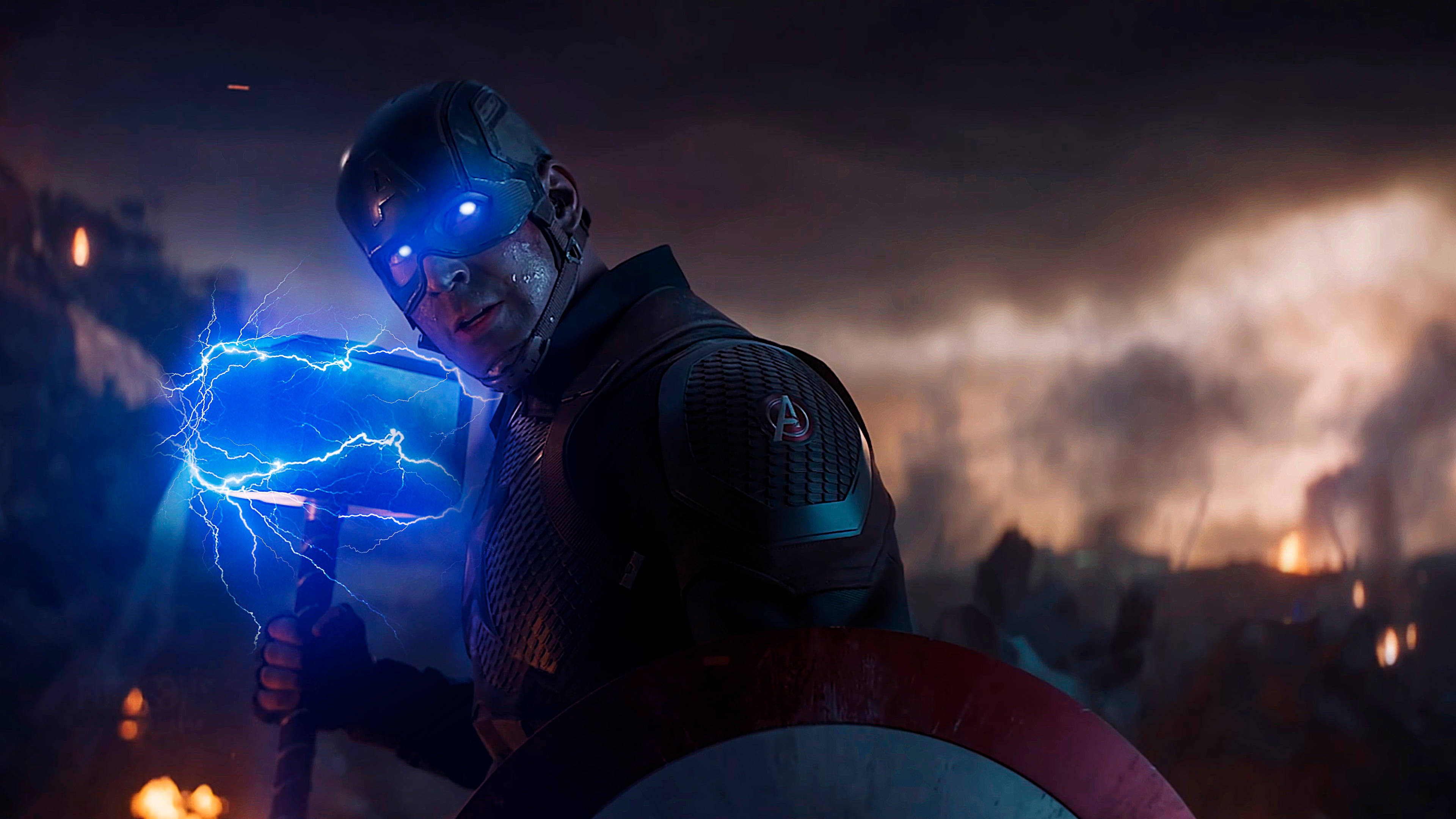 Marvel Captain America 桌布 壁紙 — 美國隊長在烈火戰場背景下揮舞著一把帶有閃電的藍色發光錘子。