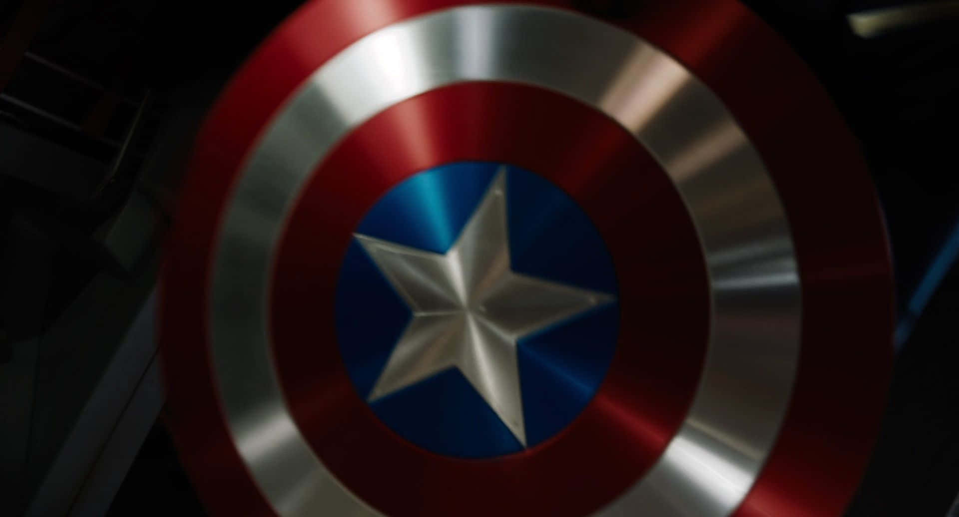 Captain America Logo 桌布 壁紙 — 美國隊長標誌性圓形盾牌的特寫，帶有紅、白、藍同心圓環和中央星星。