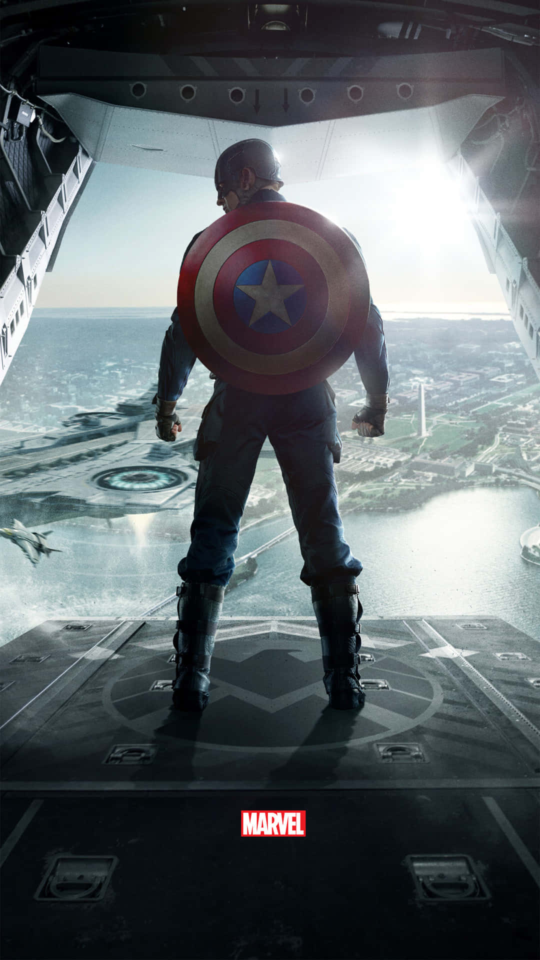 Captain America Android 桌布 壁紙 — 美國隊長站在軍用飛機的開放坡道上，俯瞰著一座沿海城市，附近有一架戰鬥機飛過。
