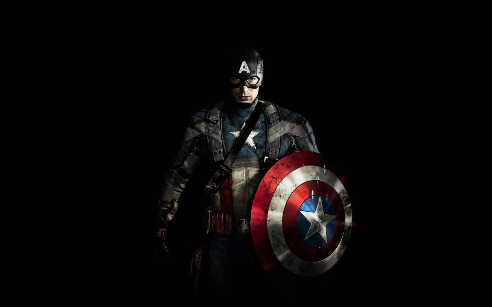 Marvel Captain America 桌布 壁紙 — 美國隊長站在黑暗中，手持標誌性的盾牌，目光堅定。