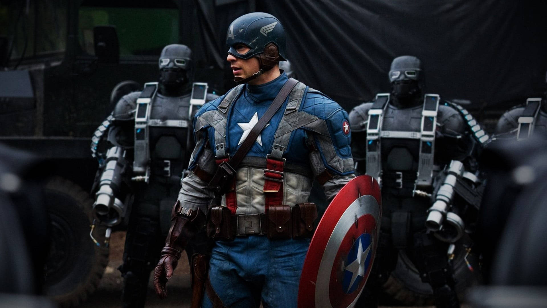 Marvel Captain America 桌布 壁紙 — 美國隊長身穿標誌性藍色星條制服，手持圓形盾牌，兩旁有身穿戰術裝備的蒙面士兵，堅定地站立。