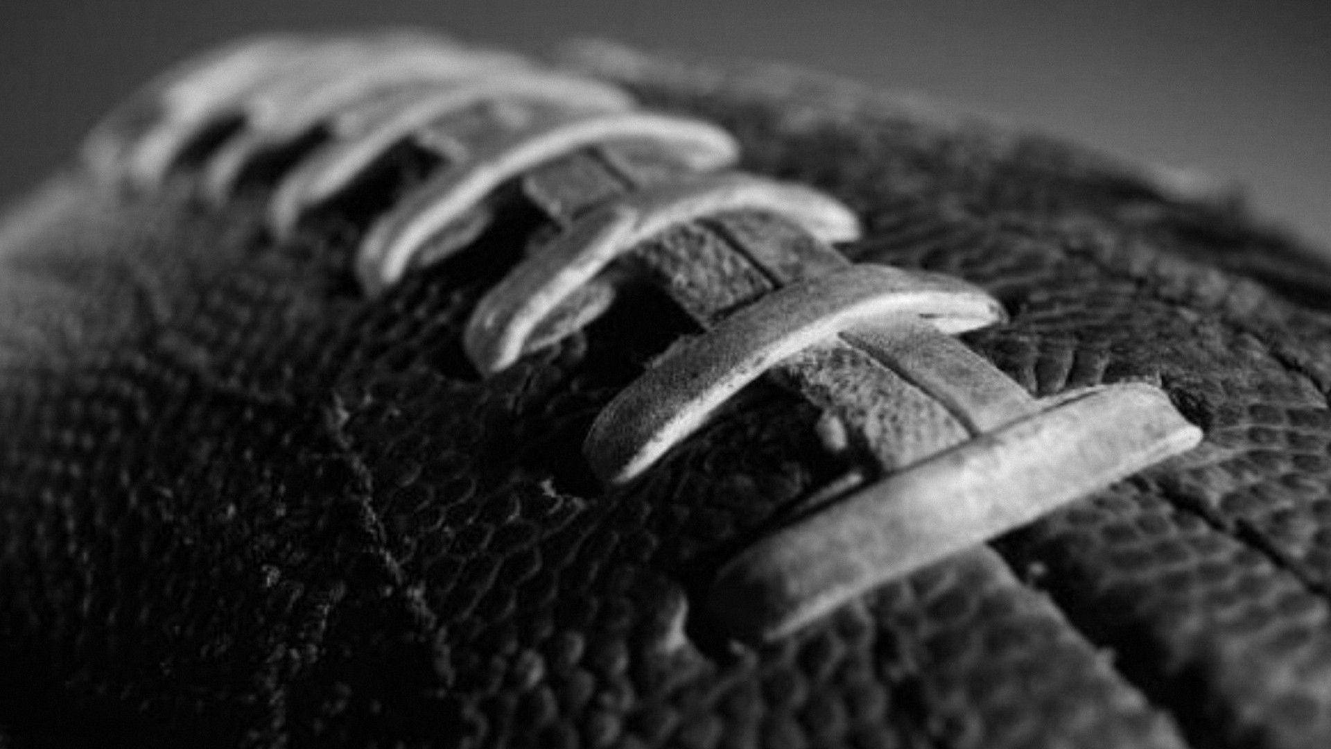 NFL 美式足球 桌布 壁紙 — 美式足球的紋理皮革和鞋帶的特寫黑白照片，顯示磨損和污垢。