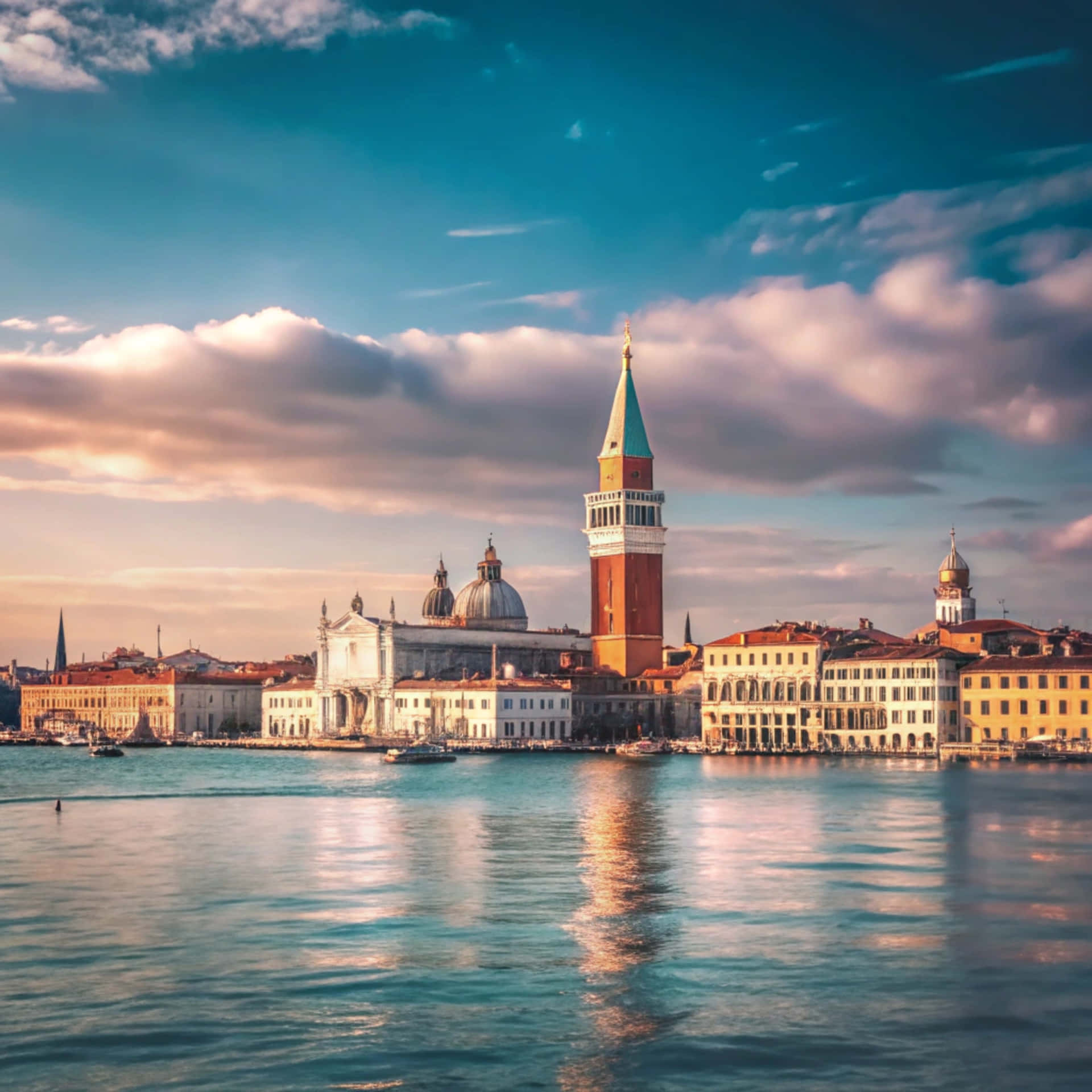 Venice Skyline 壁紙 — 義大利威尼斯日落時分，聖馬可鐘樓聳立於歷史建築之上，倒映在平靜的運河水中。
