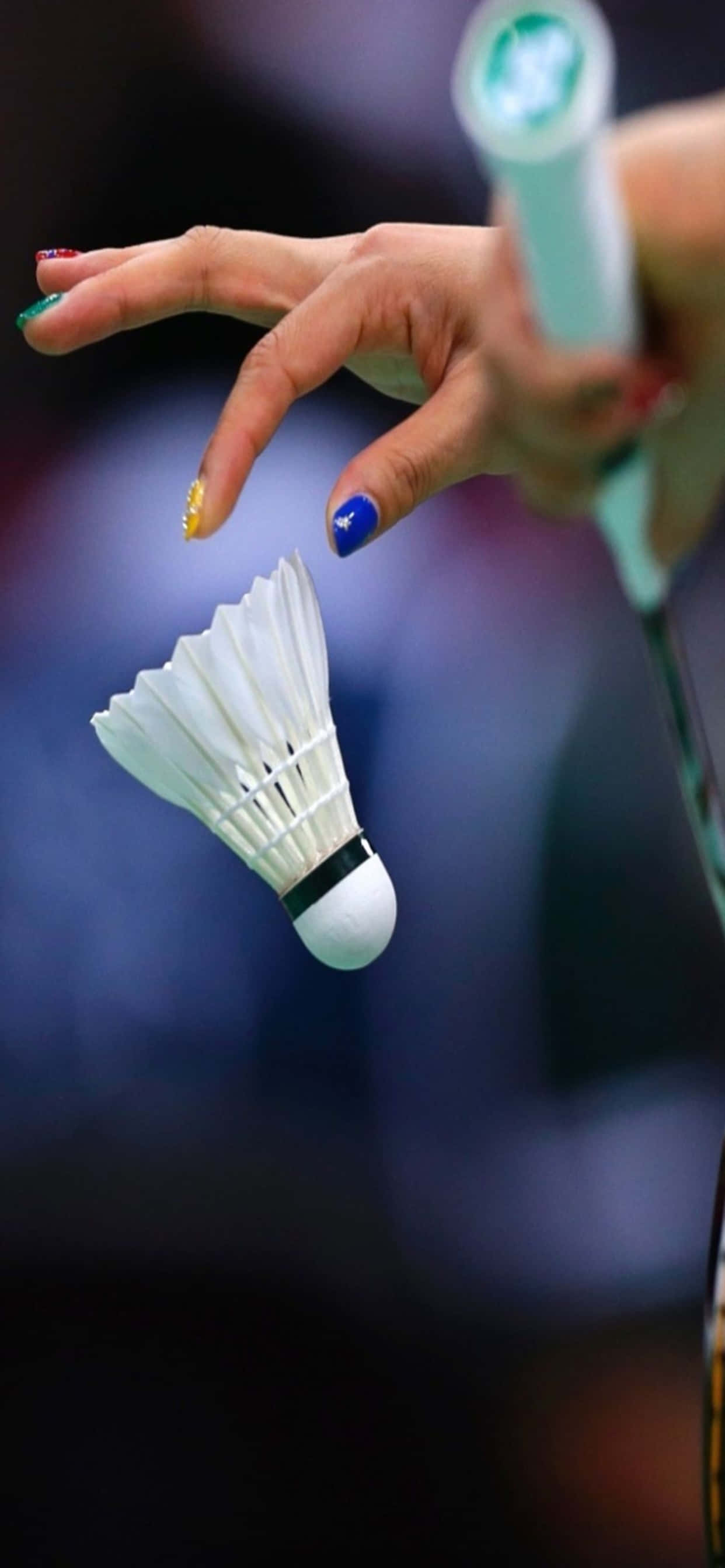 iPhone Xs Max Badminton 桌布 壁紙 — 羽毛球比賽中，球員的手部特寫，色彩繽紛的指甲優雅地懸停在半空的羽毛球上方。