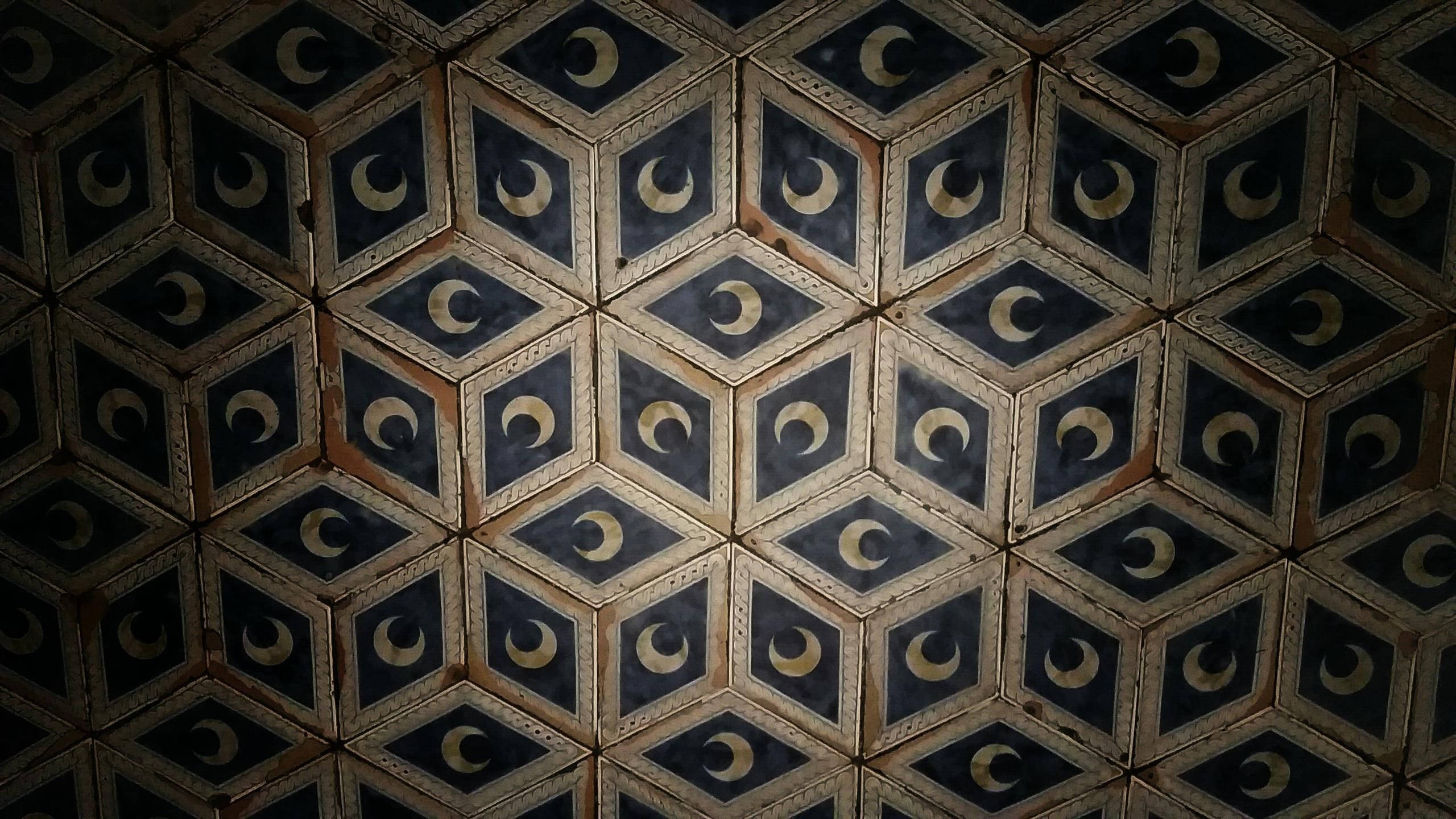 Floor Tiles 桌布 壁紙 — 老化天花板的特寫，重複的菱形面板，每個面板在深藍色上都有金色的新月圖案。