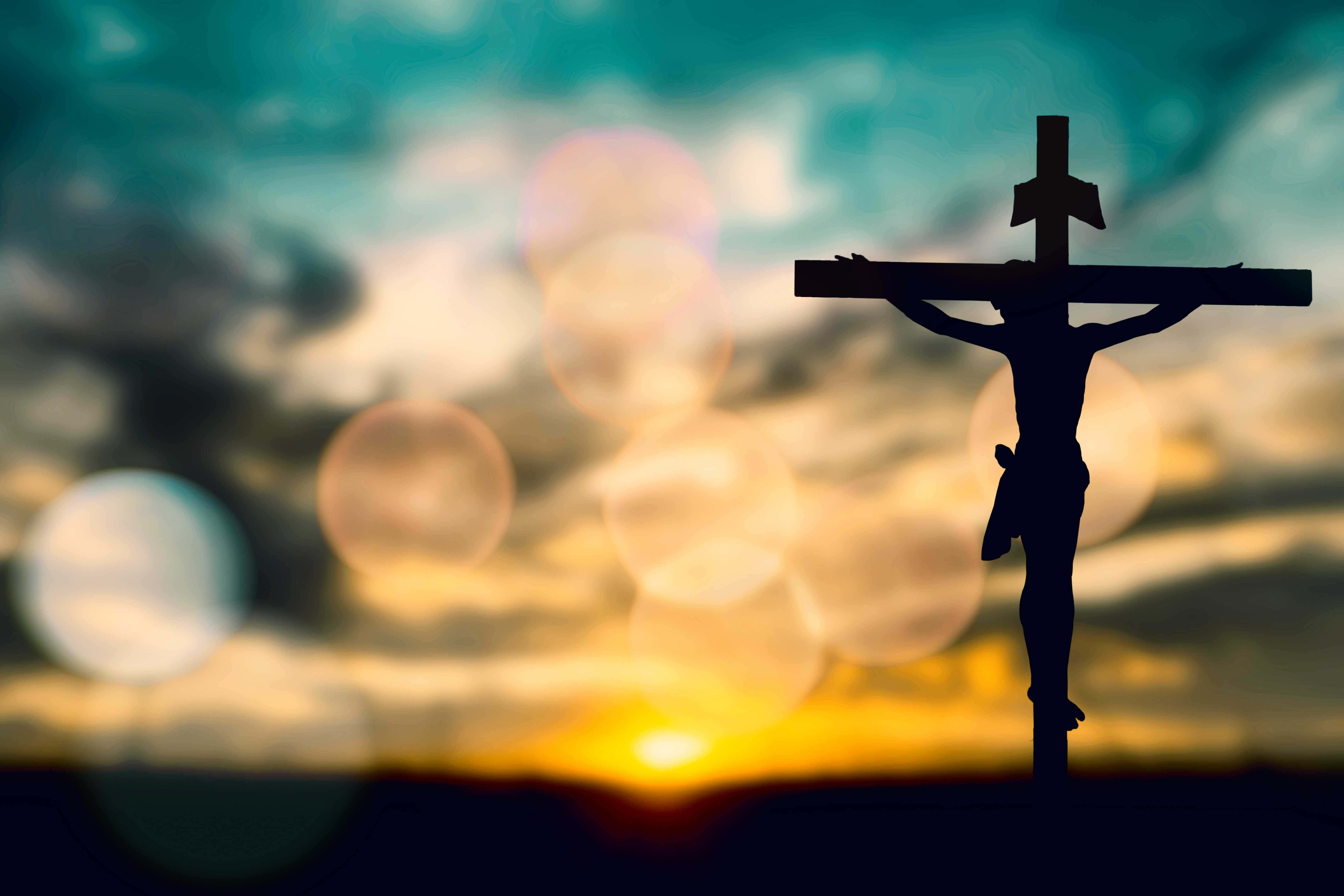 Son Of God 桌布 壁紙 — 耶穌在十字架上的剪影，映襯著充滿活力的日落天空和發光的散景燈光。