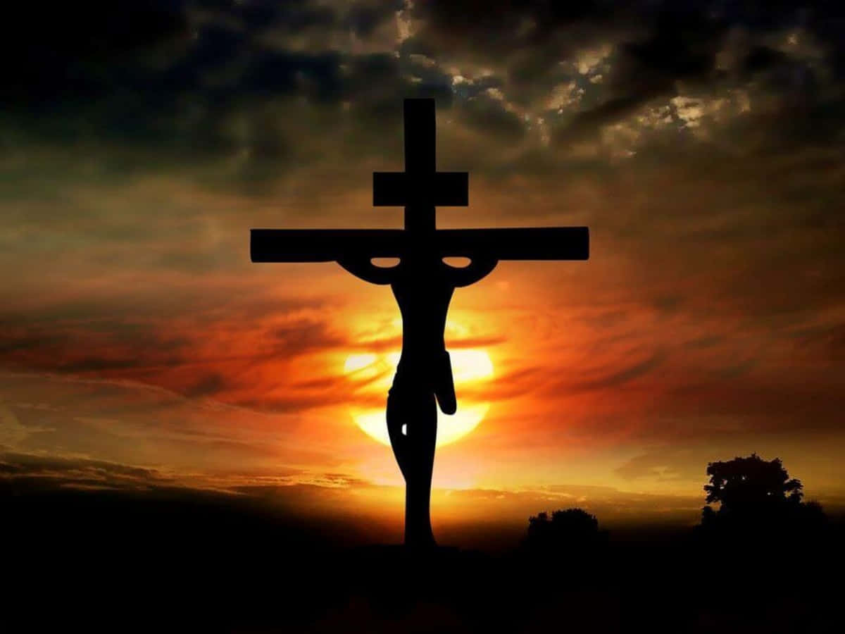 Beautiful Cross 桌布 壁紙 — 耶穌在十字架上的剪影，背景是壯麗的日落天空，帶有火紅橙色的雲彩。