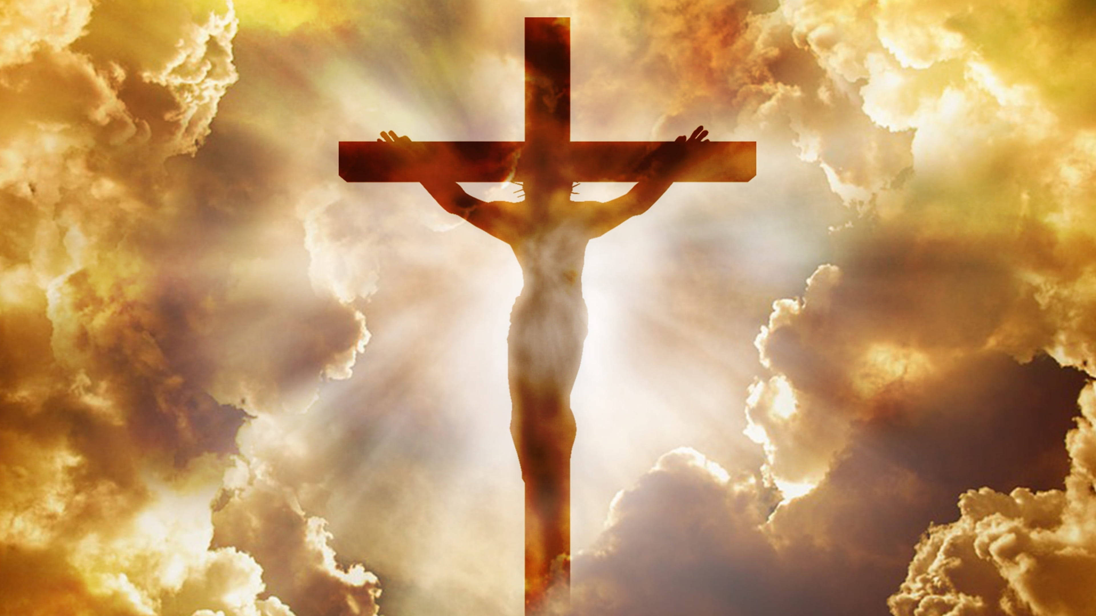Jesus Cross 桌布 壁紙 — 耶穌在十字架上的剪影，背景是燦爛的金色天空，帶有戲劇性的雲彩和神聖的光芒。