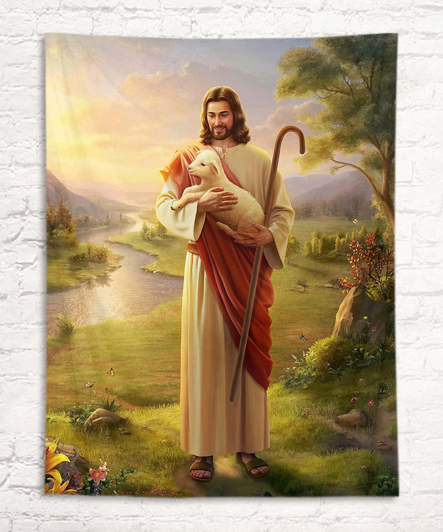 Jesus With Sheep 桌布 壁紙 — 耶穌基督在田園風光中溫柔地抱著一隻羔羊，背景有蜿蜒的河流和山脈，天空是金色的日落。