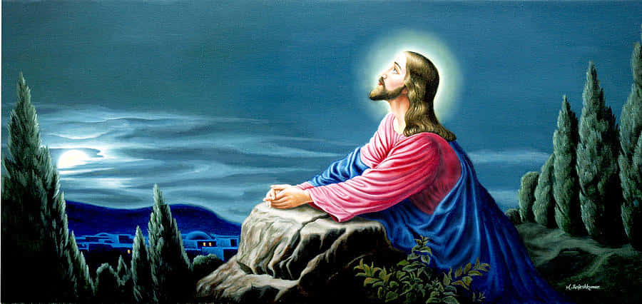 Jesus Praying 桌布 壁紙 — 耶穌基督坐在月光下的岩石山坡上，散發著光環，周圍環繞著柏樹和遠處的村莊燈光。