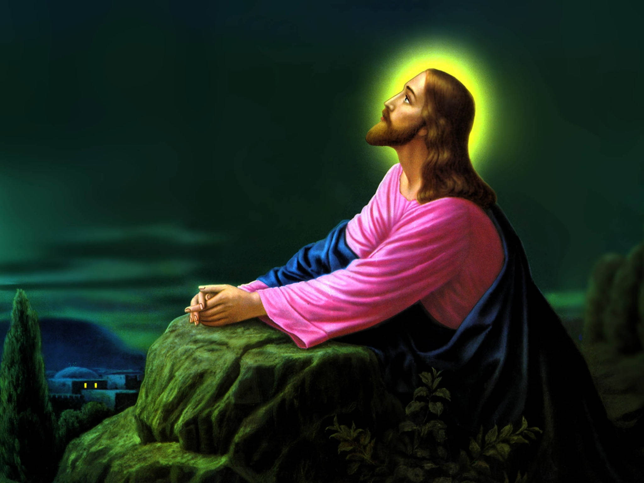 Christ 桌布 壁紙 — 耶穌基督跪在長滿苔蘚的石頭上祈禱，散發著光環，俯瞰著深綠色天空下遠處的村莊。