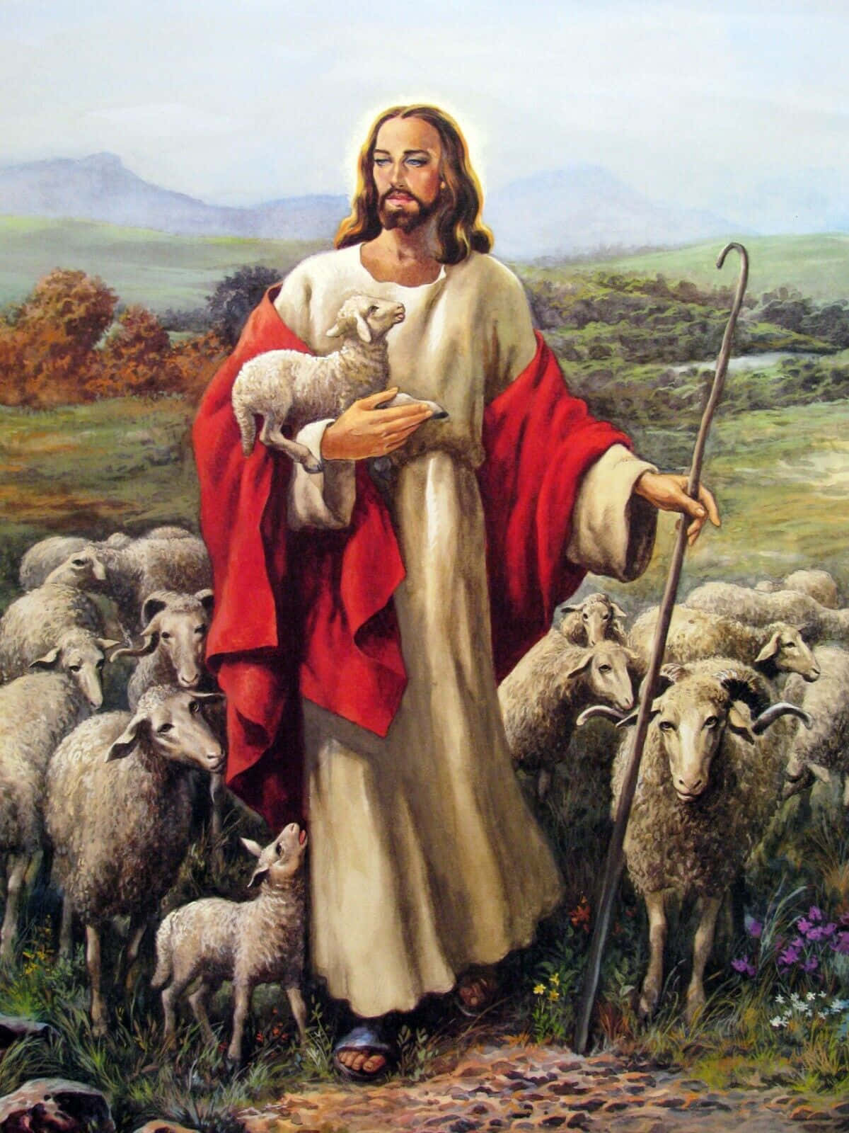 Jesus With Sheep 桌布 壁紙 — 耶穌基督身穿紅色長袍，在田園風光中溫柔地抱著一隻羔羊，周圍有羊群，遠方有山丘。