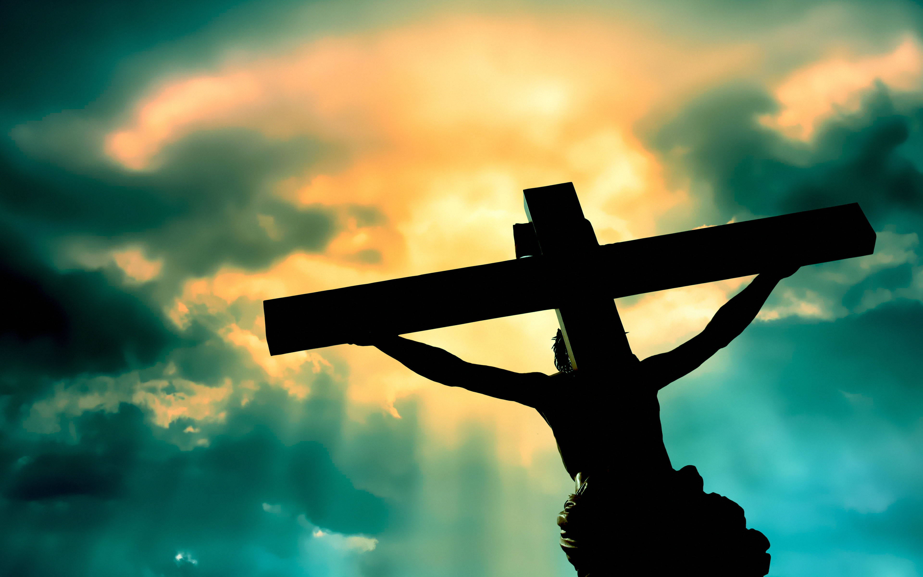 Christ 桌布 壁紙 — 耶穌背負十字架的剪影，背景是戲劇性的日落天空，金色光線穿透烏雲。