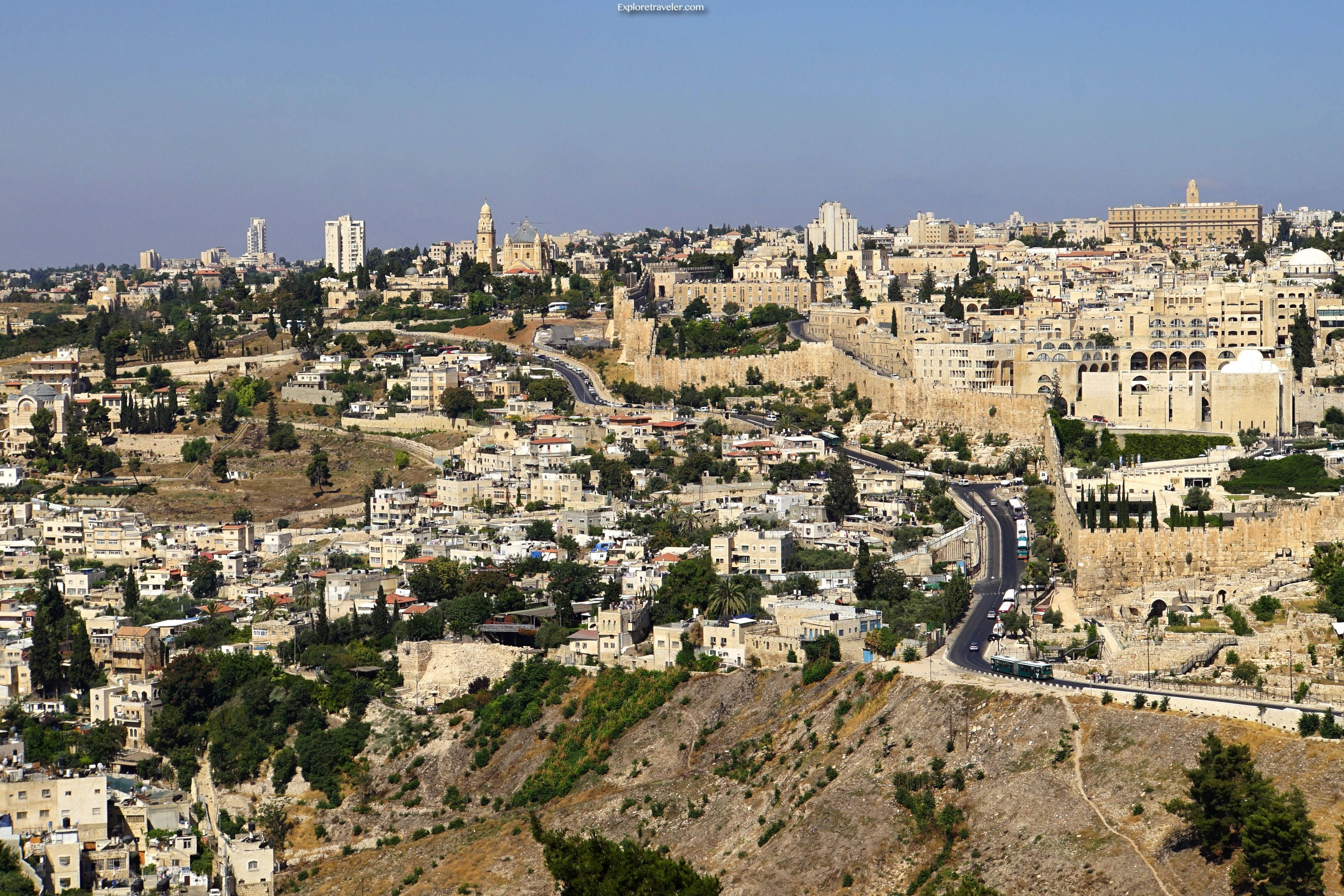 Israel 桌布 壁紙 — 耶路撒冷古城石牆與現代建築的全景，坐落於陽光普照的山丘上，天空清澈湛藍。