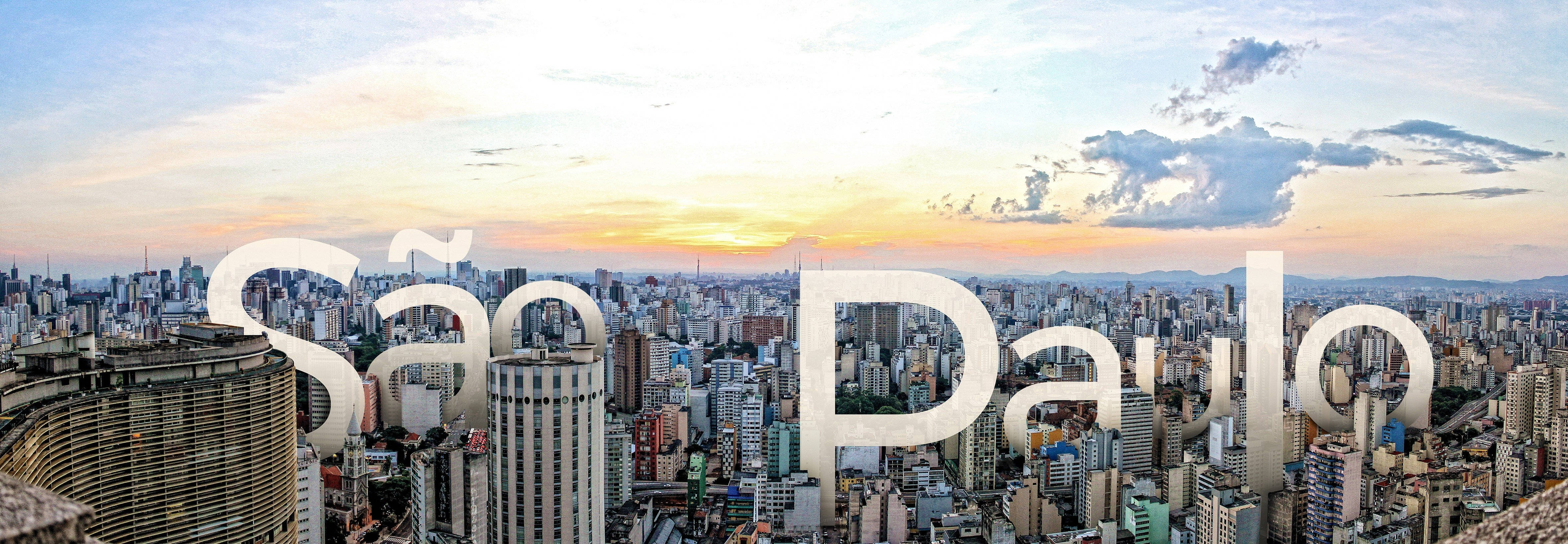 聖保羅 桌布 壁紙 — 聖保羅密集城市天際線的全景日落景觀，高聳建築與柔和橙色雲彩。
