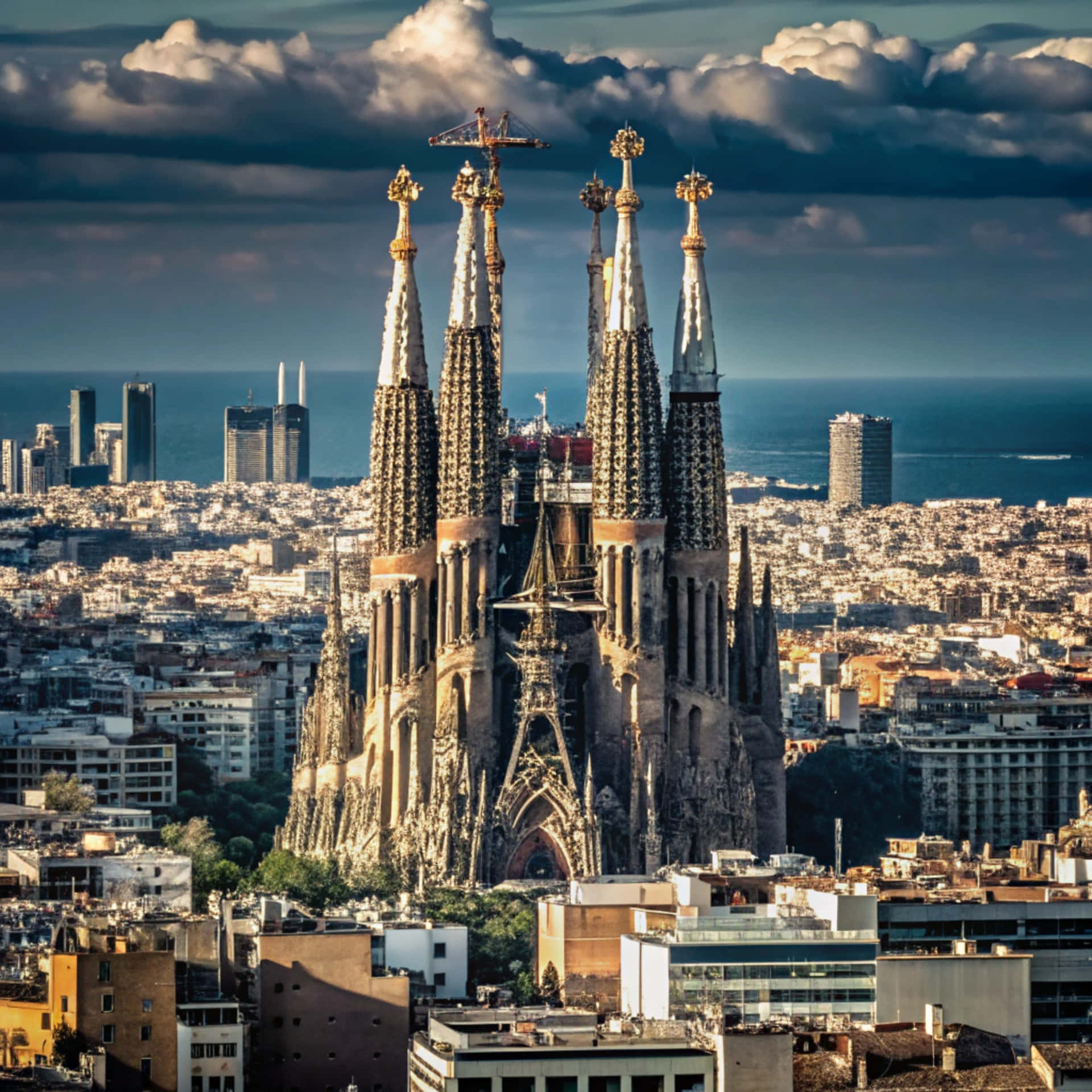 Sagrada Familia 壁紙 — 聖家堂大教堂的塔樓在戲劇性的多雲天空下，聳立在巴塞隆納城市景觀之上，遠處可見大海。