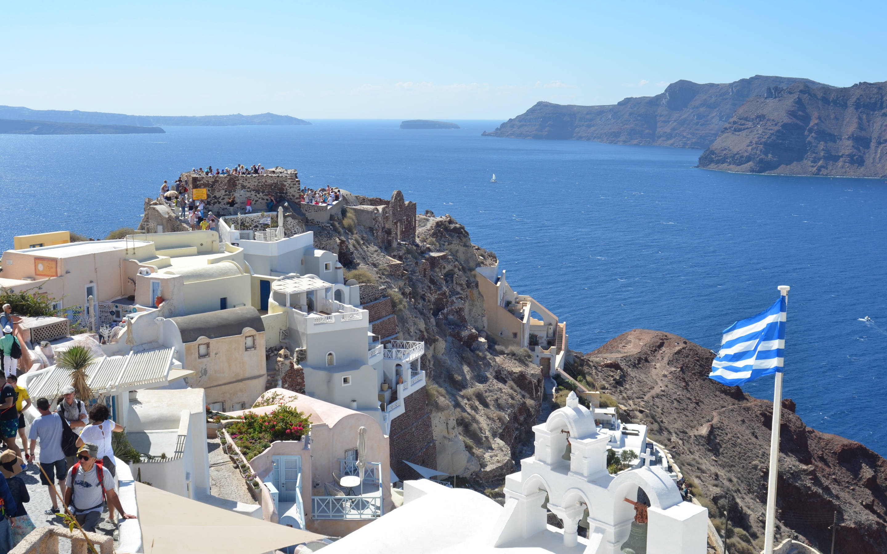 greek 桌布 壁紙 — 聖托里尼伊亞的白色懸崖建築，在晴朗的天空下俯瞰深藍色的愛琴海。
