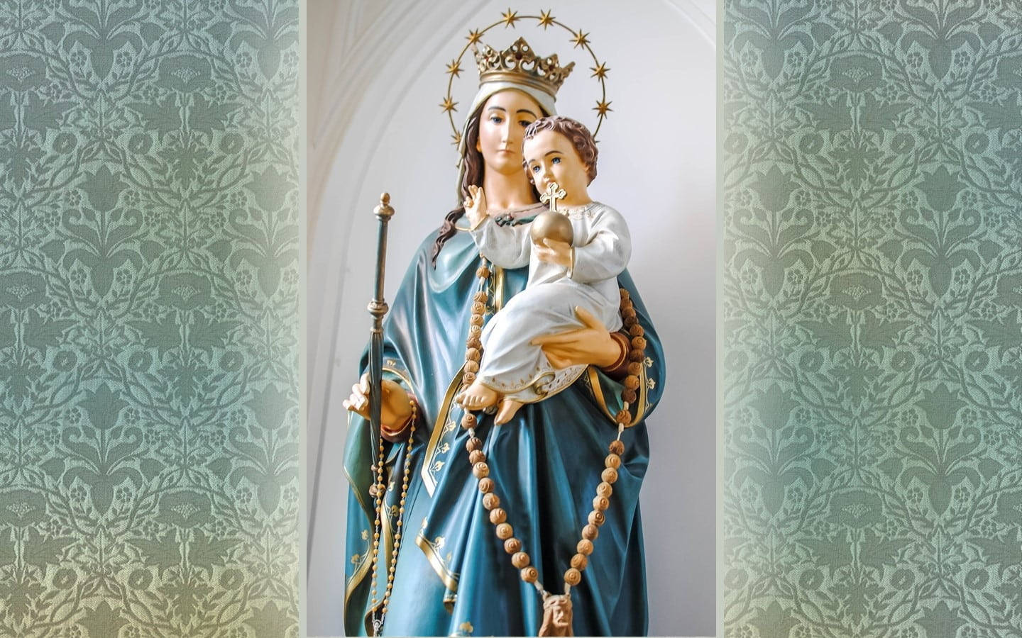 Mary 桌布 壁紙 — 聖母瑪利亞懷抱嬰兒耶穌的寧靜雕像，以華麗的藍綠色大馬士革花紋壁紙為背景。