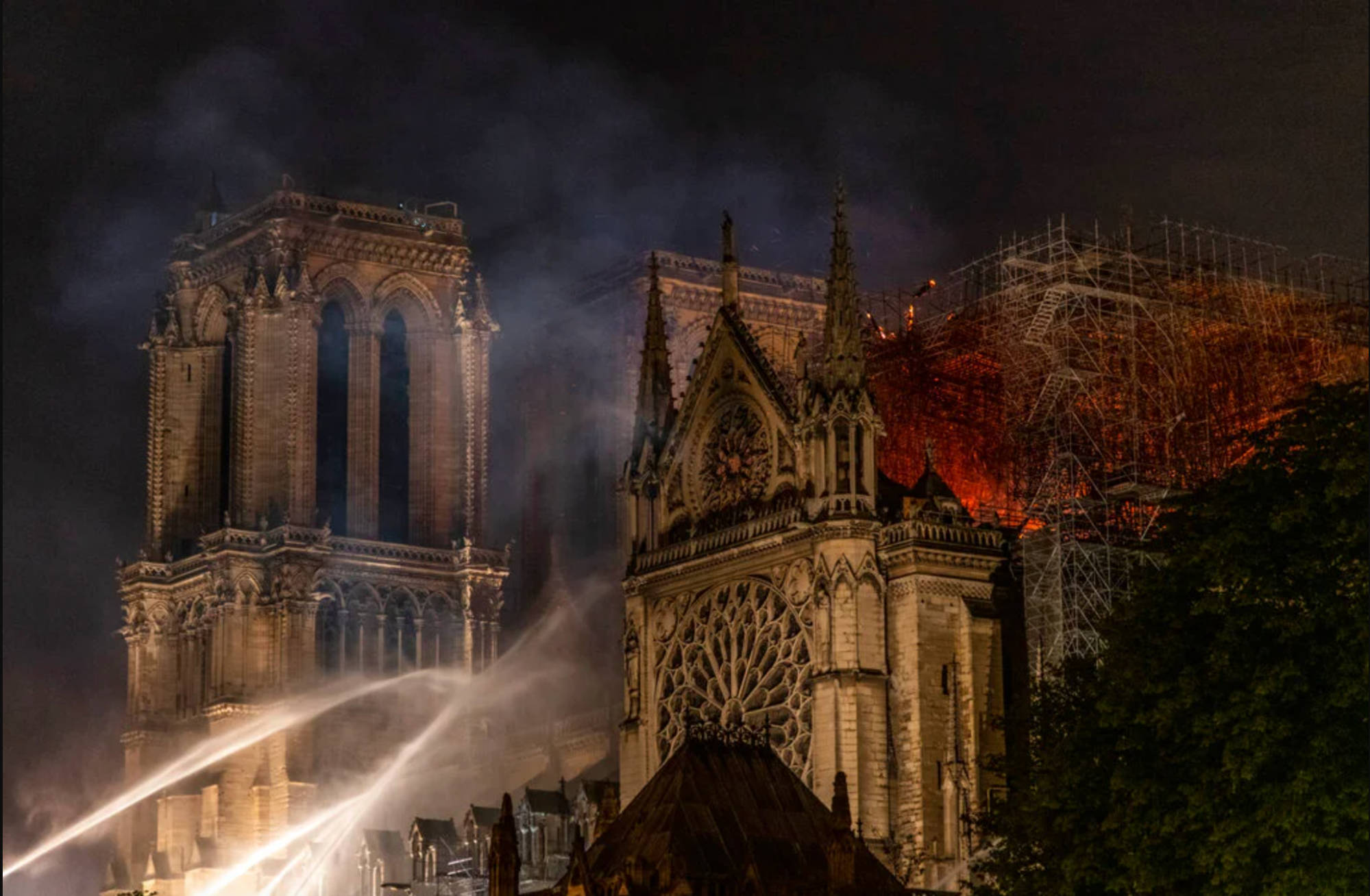 Notre Dame 桌布 壁紙 — 聖母院在夜間燃燒，消防員奮力撲滅吞噬屋頂和棚架的火焰。