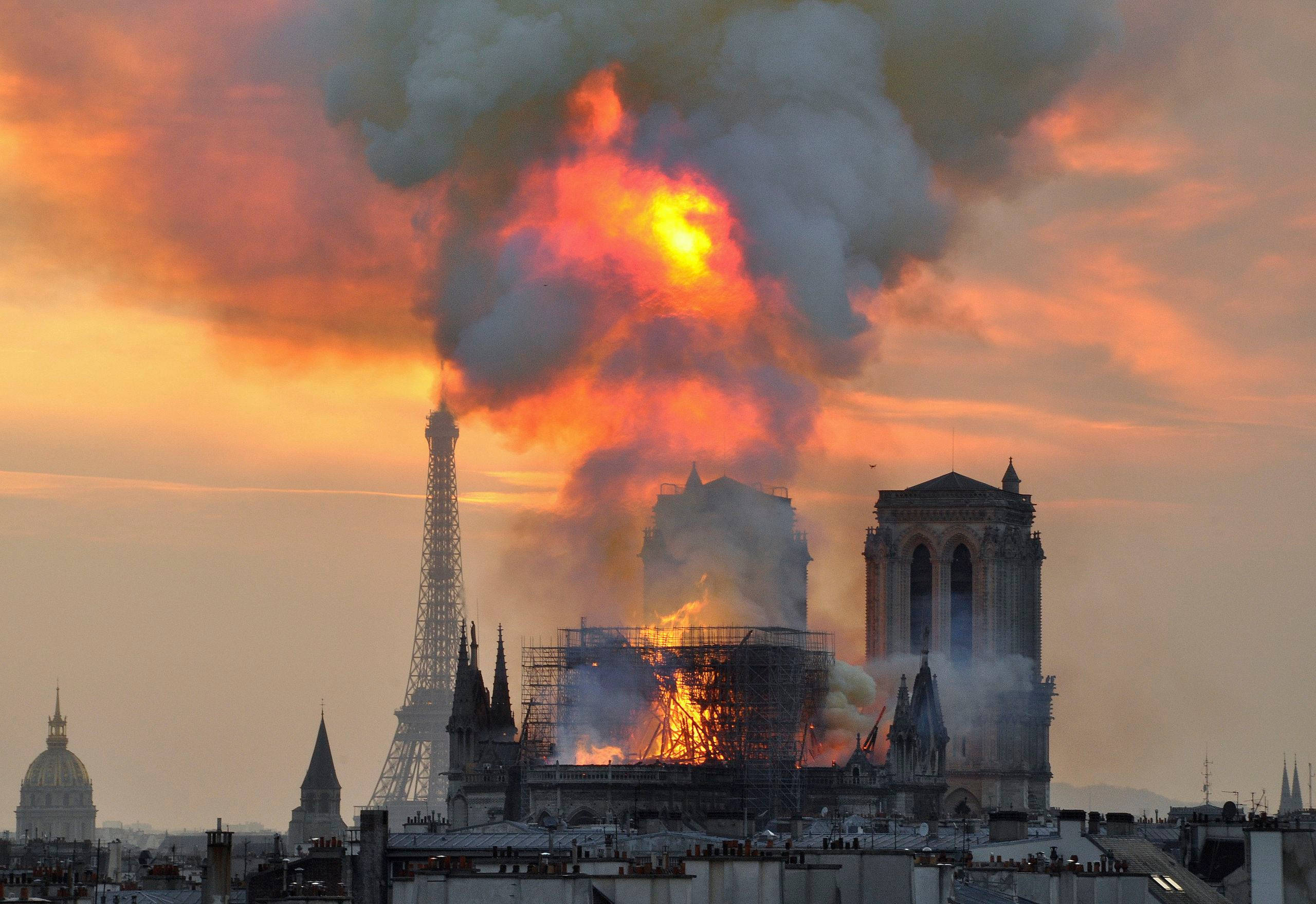 Notre Dame 桌布 壁紙 — 聖母院在日落時猛烈燃燒，濃煙升騰，艾菲爾鐵塔矗立在附近。