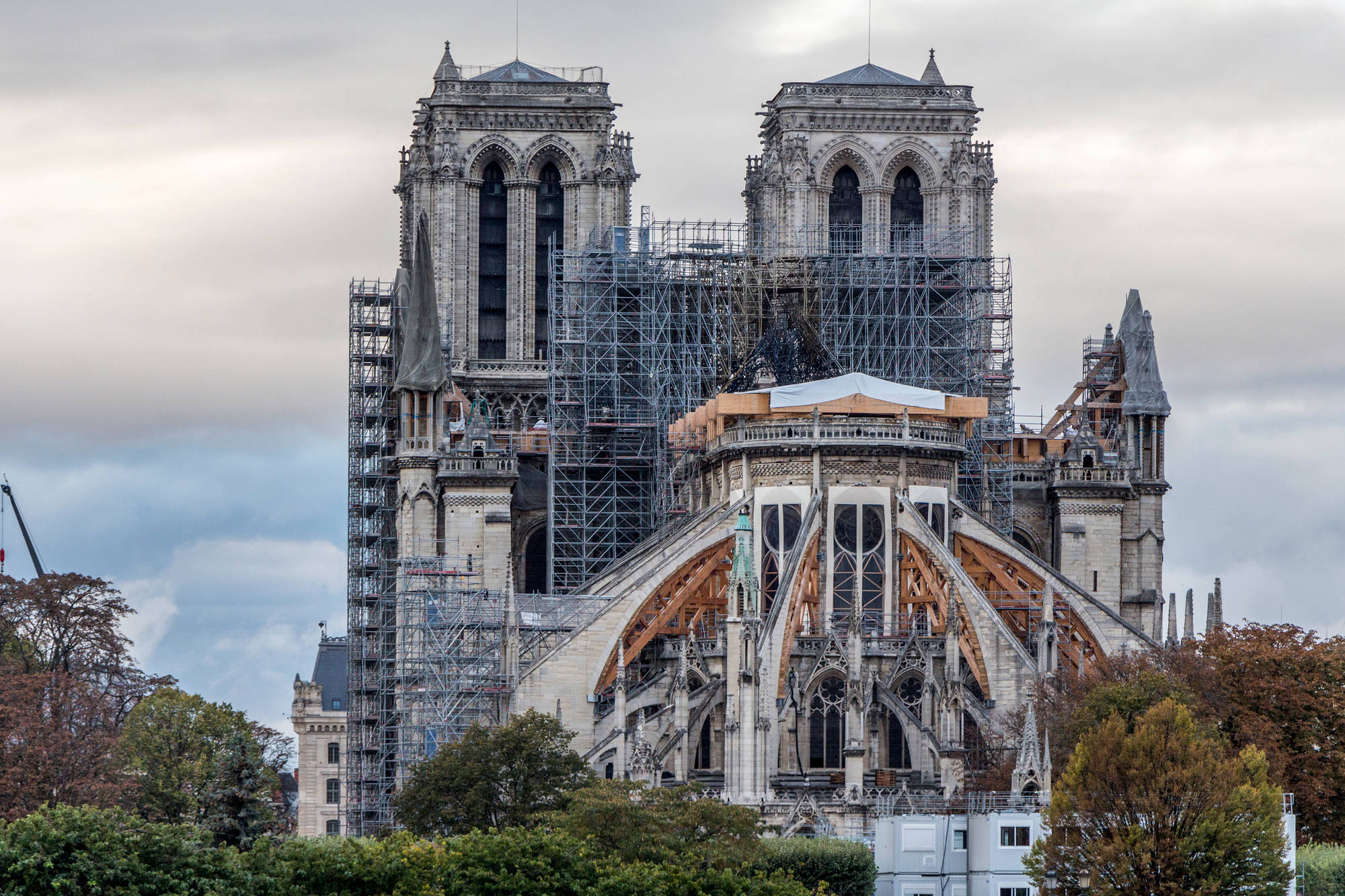 Notre Dame 桌布 壁紙 — 聖母院大教堂正在修復中，有鷹架和裸露的木樑，背景是陰天。