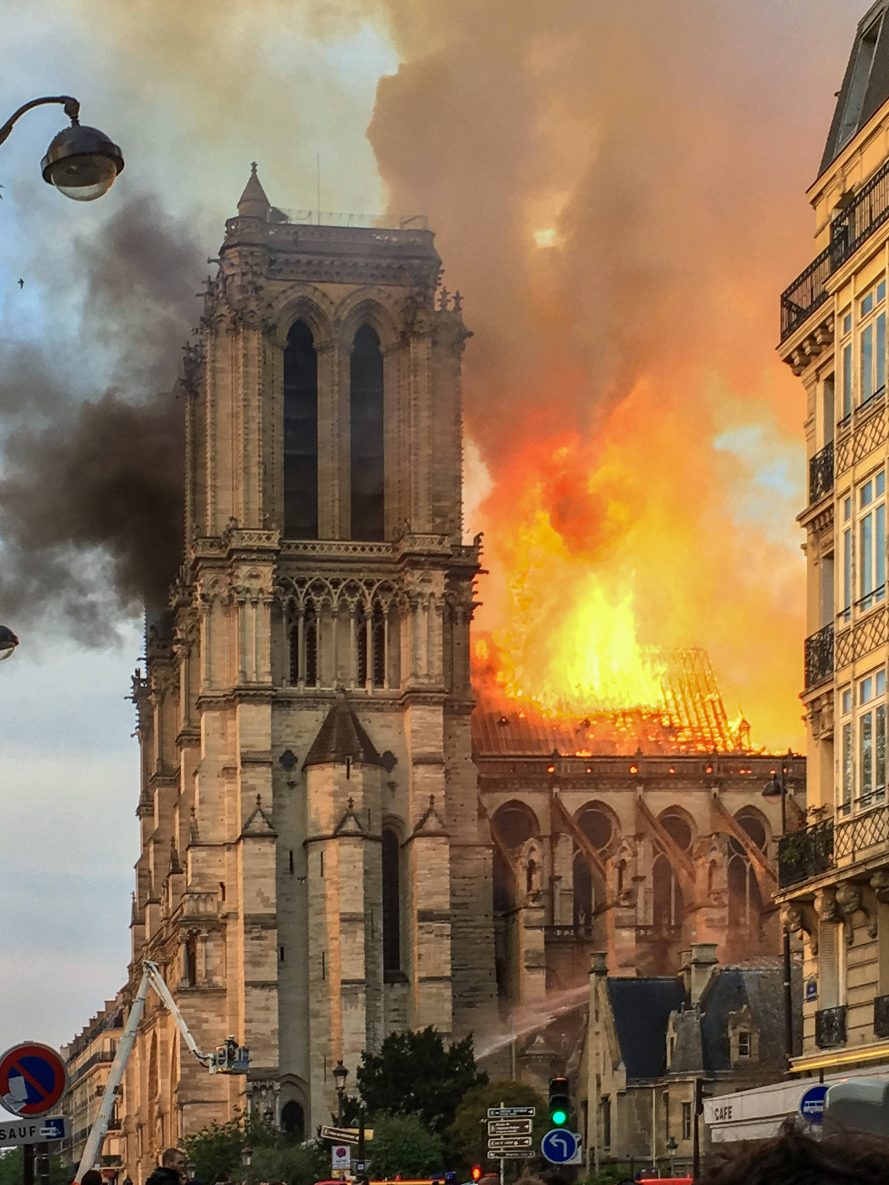Notre Dame 桌布 壁紙 — 聖母院大教堂猛烈燃燒，橙色火焰和濃黑煙霧在陰天背景下翻滾，消防員正在撲滅大火。