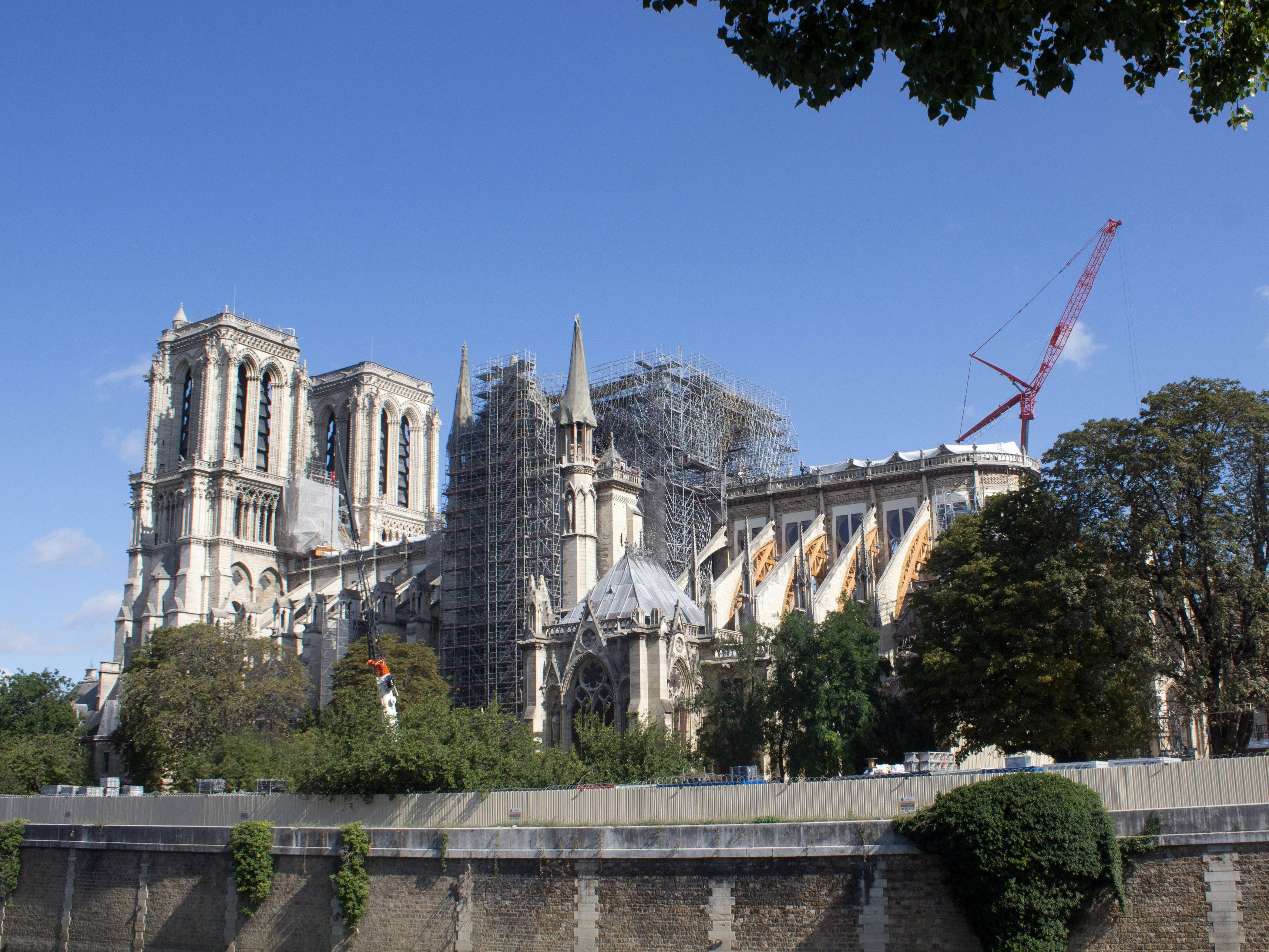 Notre Dame 桌布 壁紙 — 聖母院正在修復，搭有鷹架和紅色起重機，背景是清澈的藍天。
