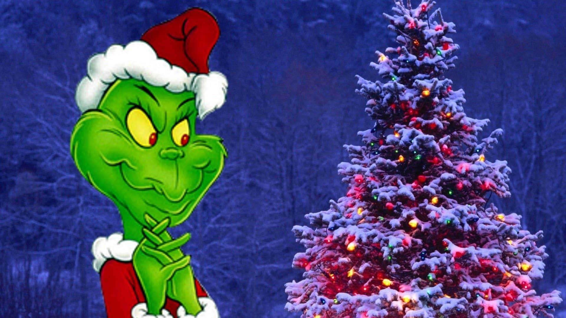 Cute Grinch 桌布 壁紙 — 聖誕怪傑戴著紅色聖誕老人帽，在黑暗的冬日樹林背景下，在掛滿彩色燈泡、積雪覆蓋的聖誕樹旁得意地笑。