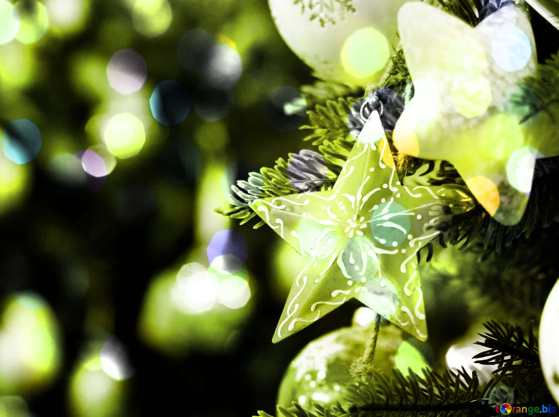 Christmas Star 桌布 壁紙 — 聖誕樹上發光綠色星星裝飾的特寫，背景有柔和散景燈光。